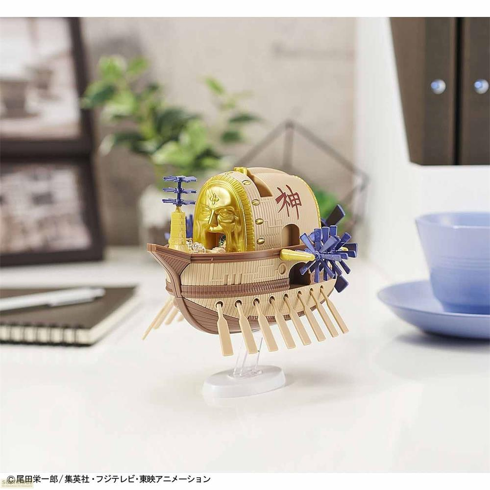 Ein detailliertes Modell der Maxim aus One Piece auf einem Ständer mit goldenem Gesicht und blauen Akzenten auf einem Schreibtisch.