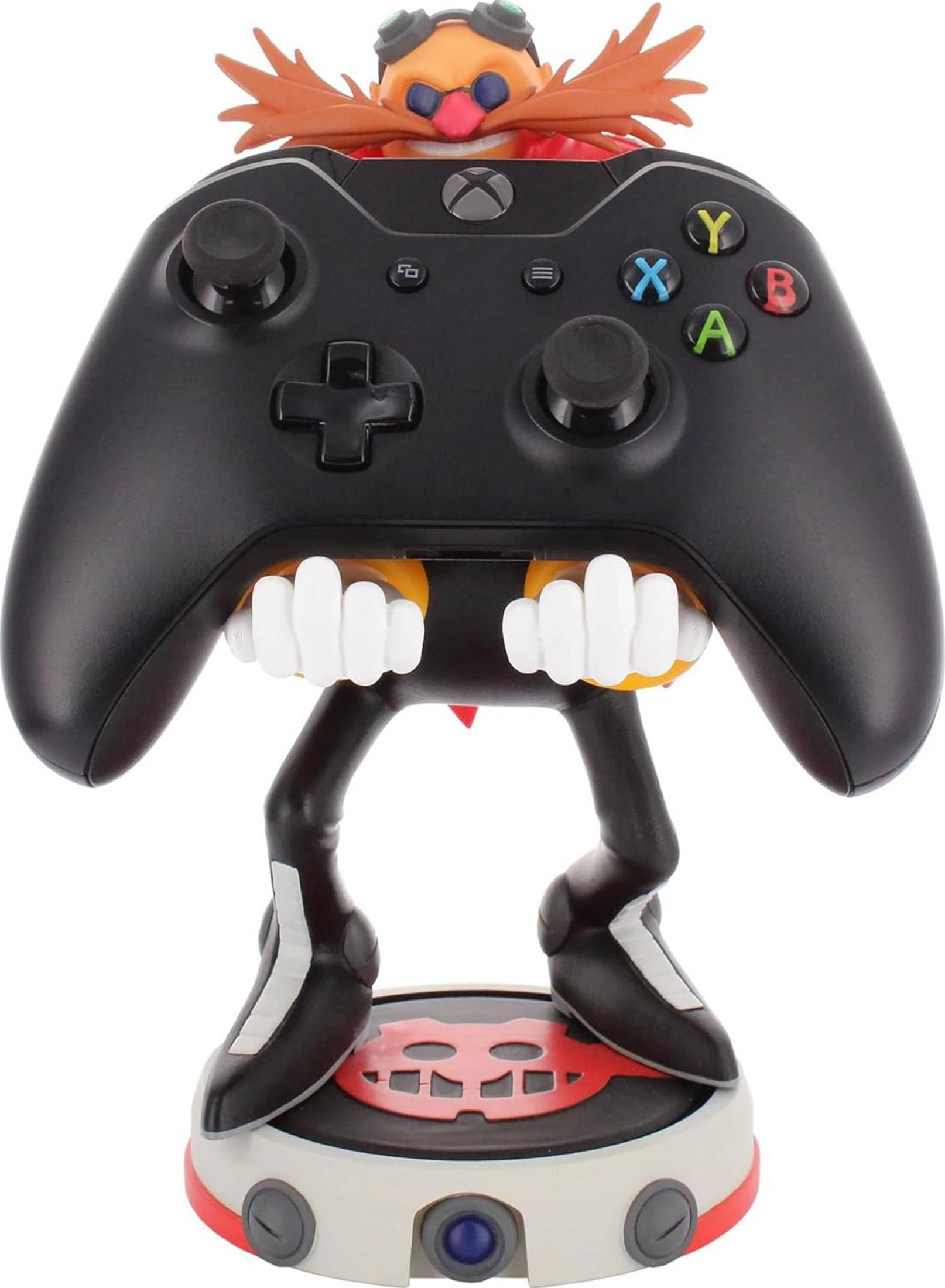 Eine Dr. Eggman-Figur hält einen schwarzen Xbox-Controller auf einem runden Ständer mit einem roten Schädel-Symbol.