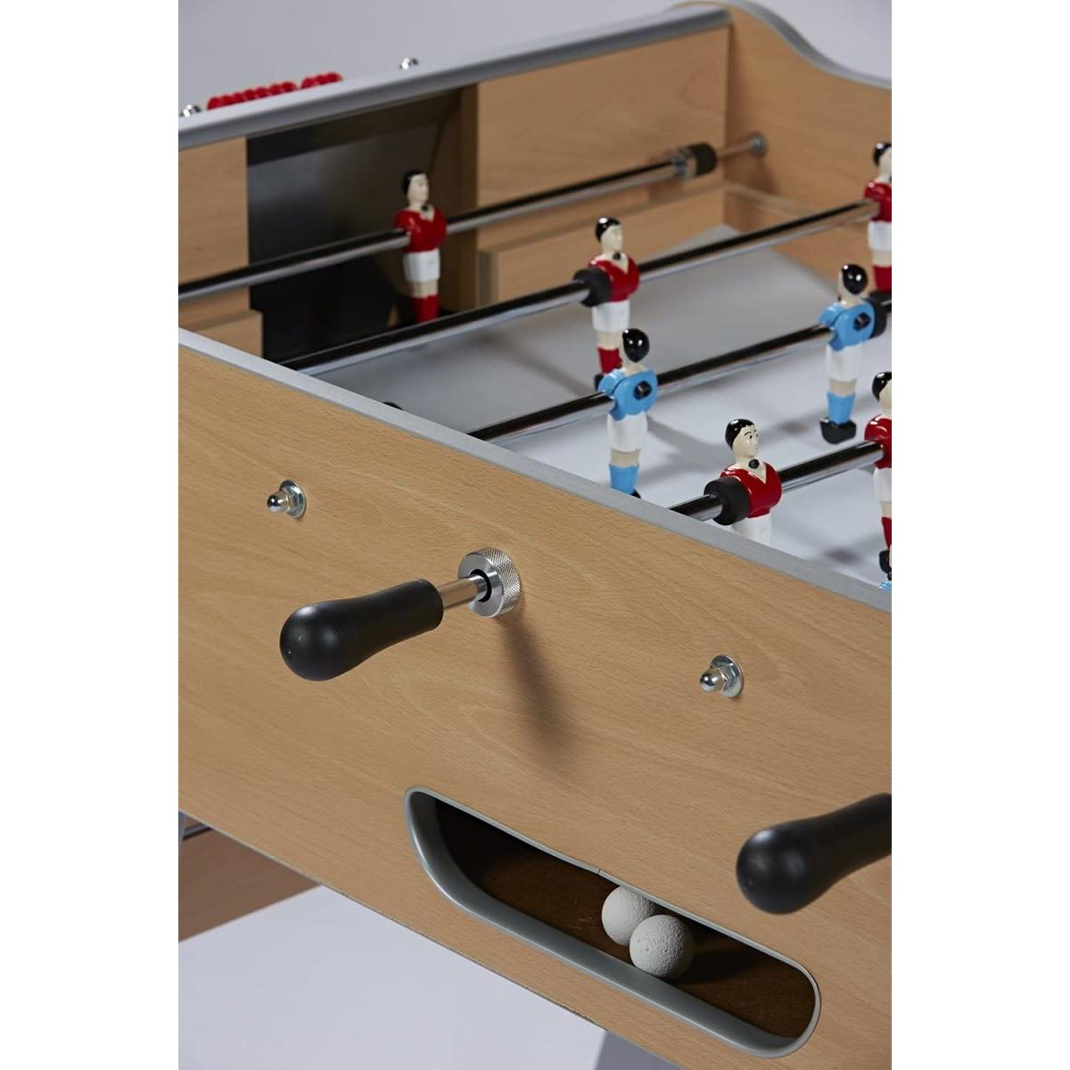 Holzfarbener Tischkicker mit roten und blauen Figuren, Metallstangen und zwei Bällen im Ausgabefach.