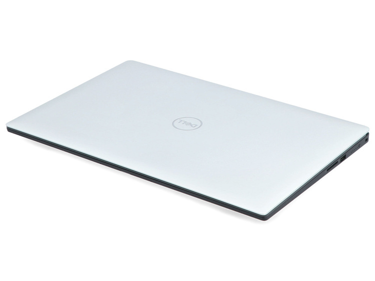 Zamknięty srebrny laptop Dell spoczywa na białej powierzchni z widocznym logo.