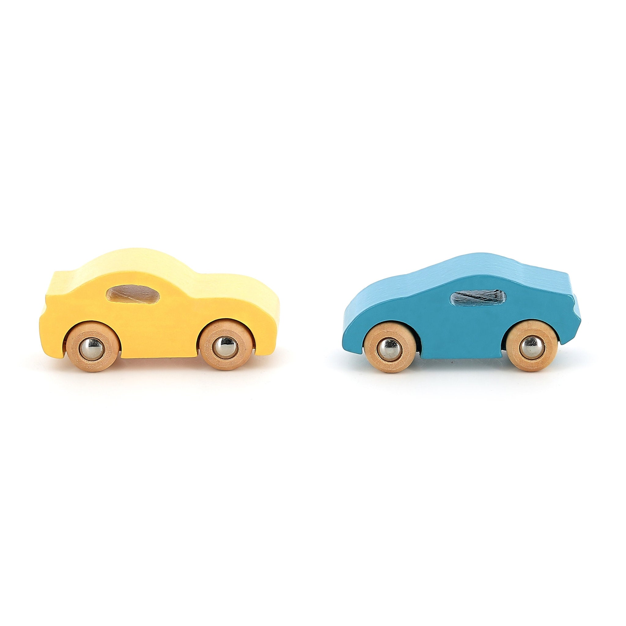 Zwei kleine Holzspielzeugautos, ein gelbes links und ein blaues rechts, stehen auf weißem Hintergrund.