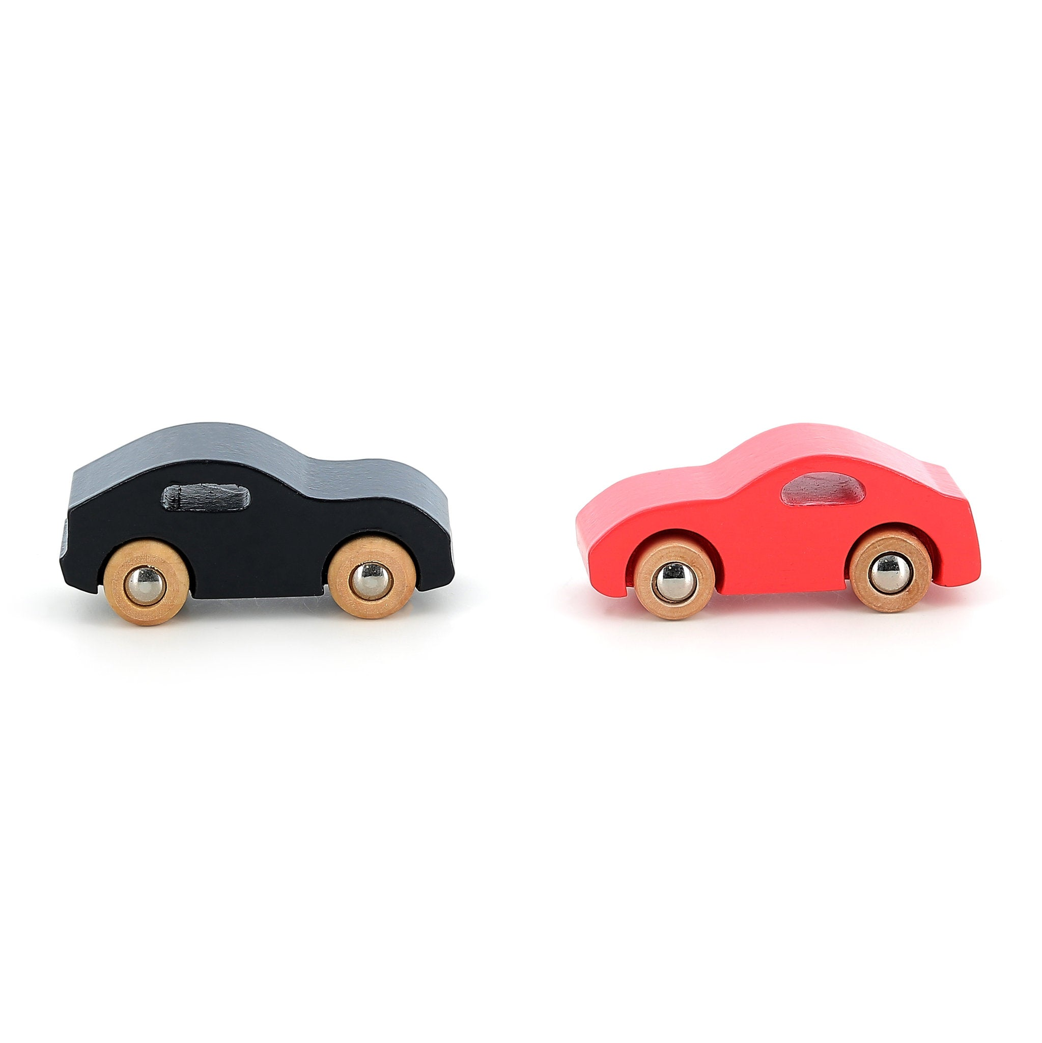 Zwei minimalistische Holzautos, eines schwarz und eines rot, stehen sich auf weißem Hintergrund gegenüber.