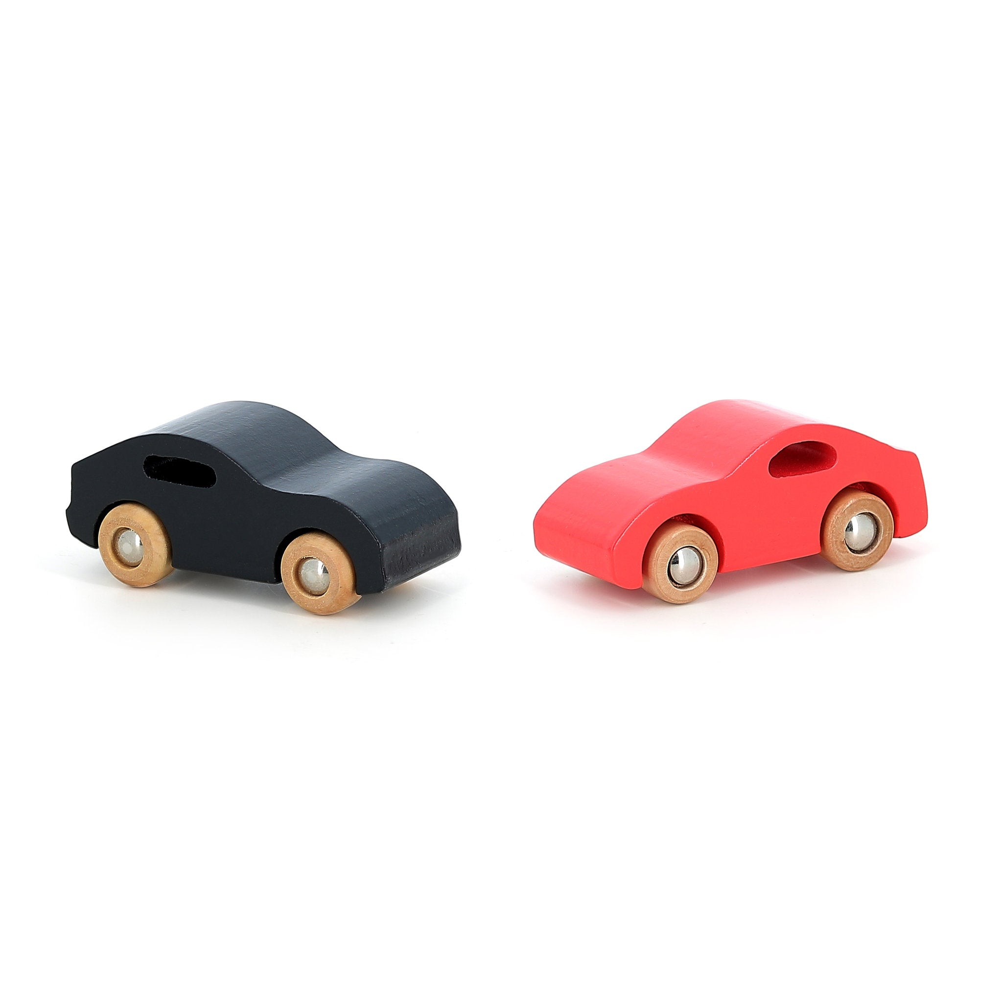 Zwei minimalistische Holzautos, eines schwarz und eines rot, stehen sich auf weißem Hintergrund gegenüber.