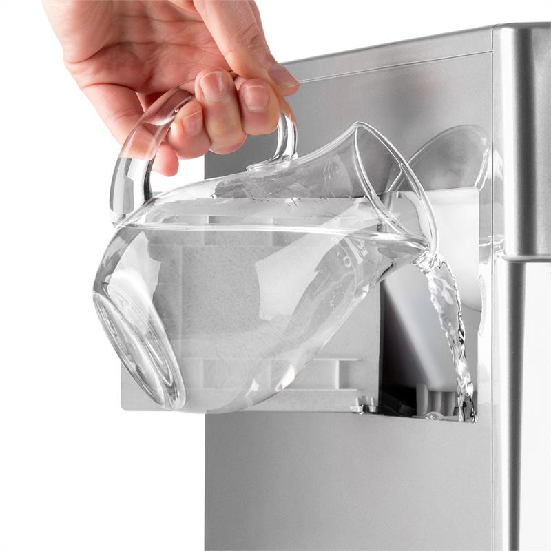 Eine Hand gießt Wasser aus einer Glas Karaffe in den Wassertank einer Kaffeemaschine.