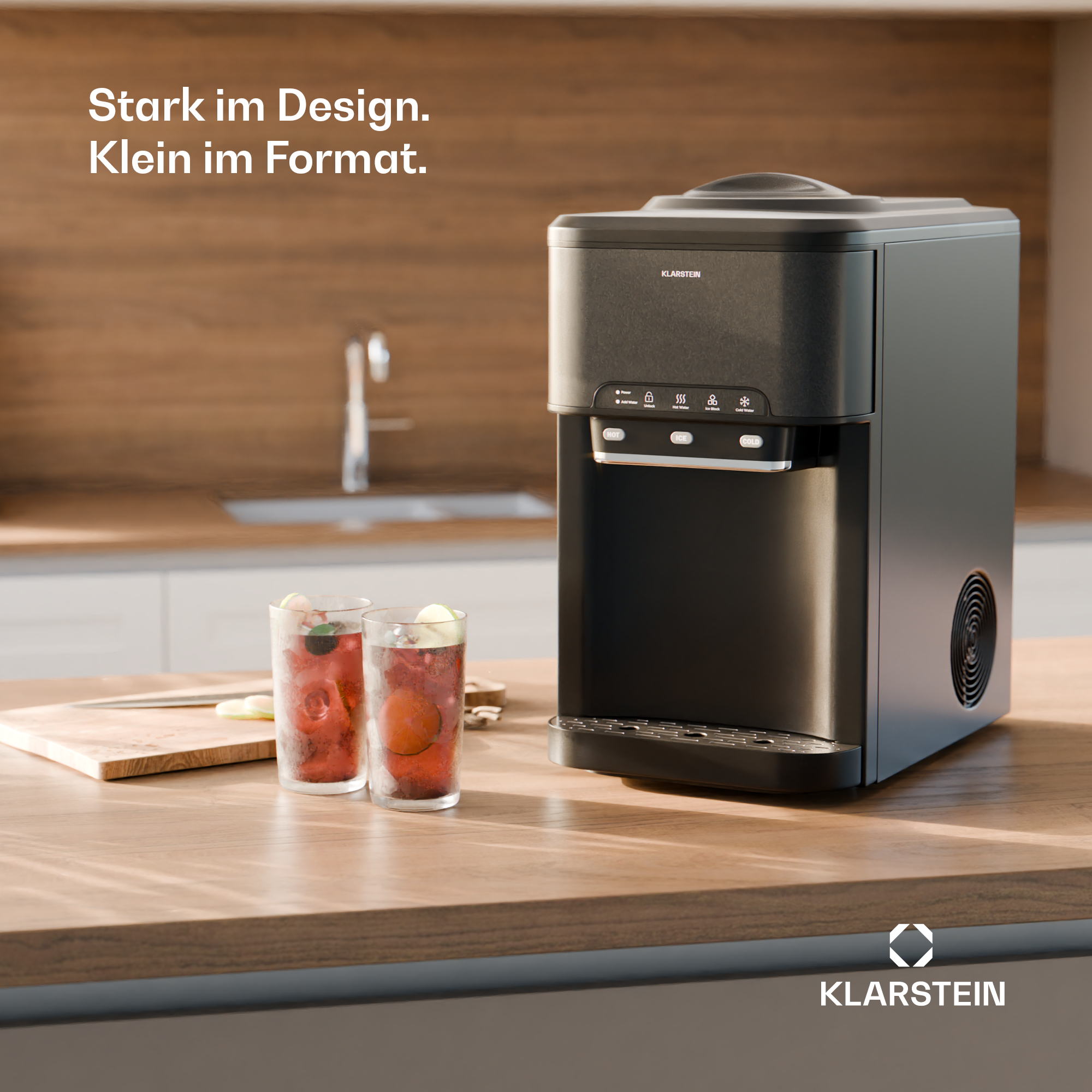 Ein schwarzer Klarstein Wasserspender steht auf einer Holzküchentheke neben zwei roten Getränken.