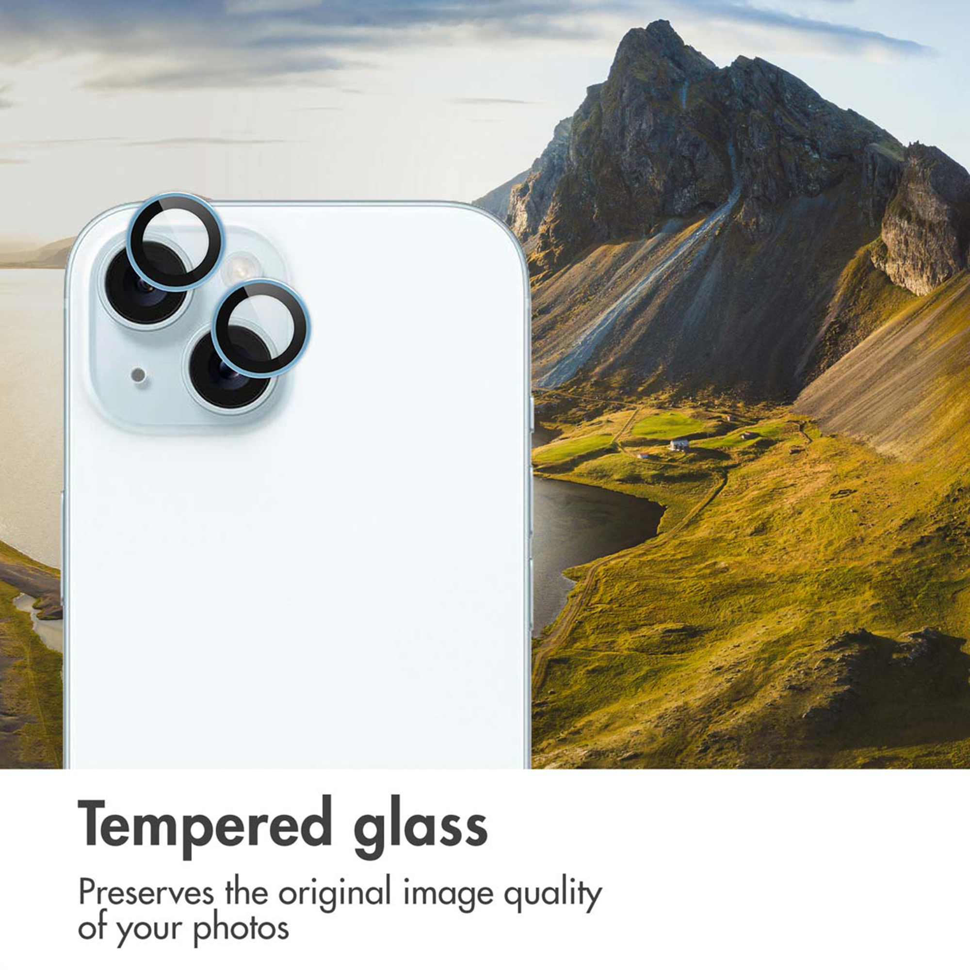 Achterkant van een witte smartphone met lensbeschermers tegen een berglandschap.