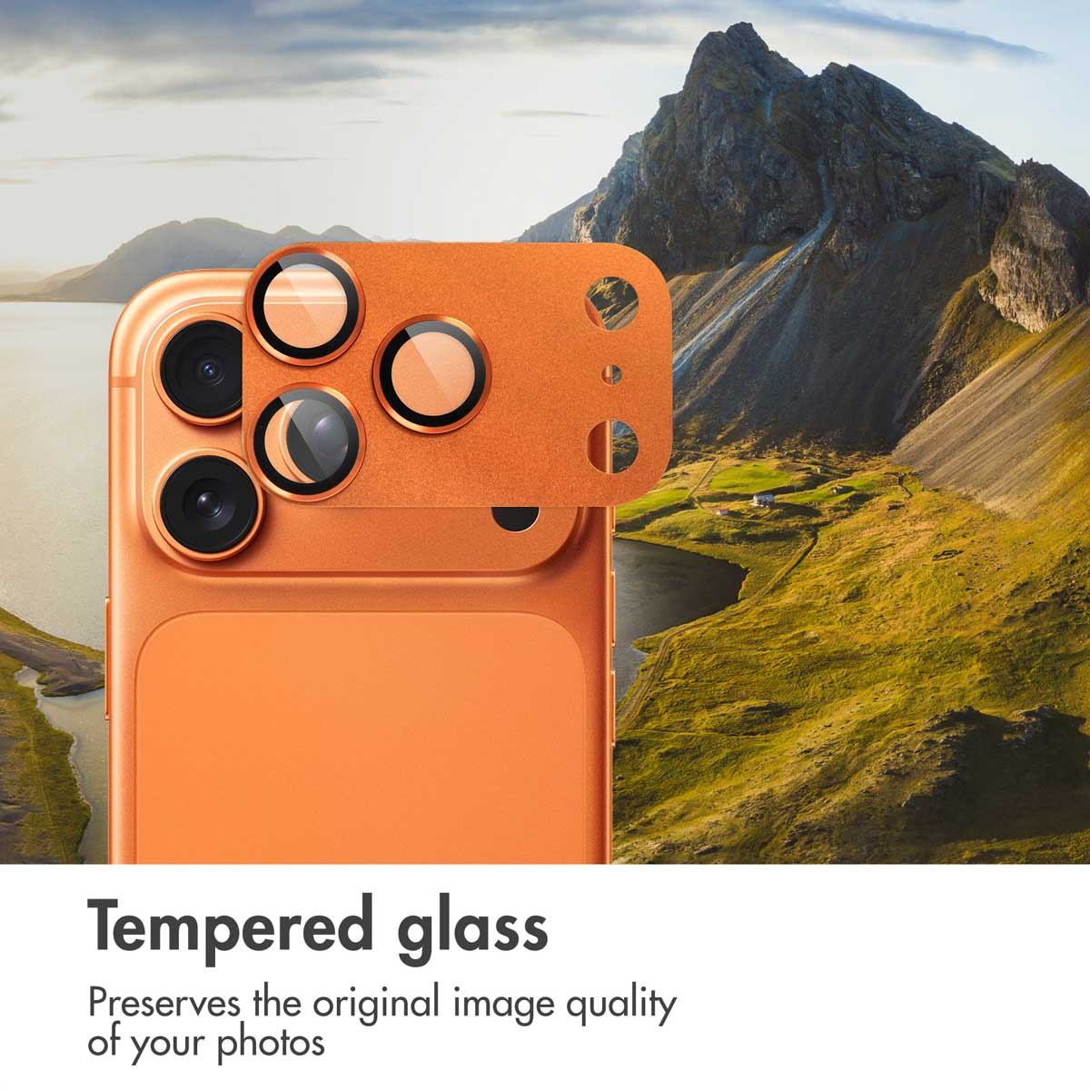 Uno smartphone arancione con protezioni per lenti di fronte a un paesaggio montano.