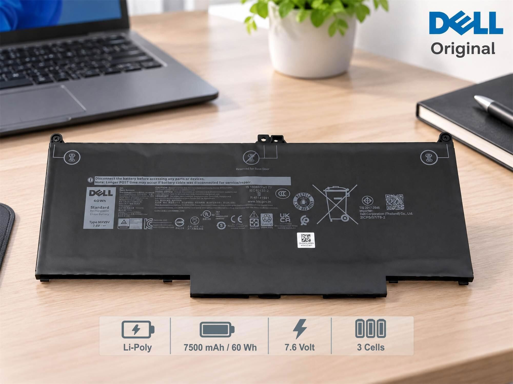 Eine schwarze Dell Original-Laptopbatterie liegt auf einem Holztisch, im Hintergrund sind ein Laptop und ein Notizbuch.
