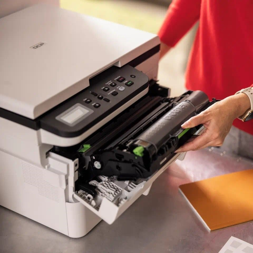 Person in rotem Oberteil ersetzt den Toner in einem weißen Multifunktionsdrucker.