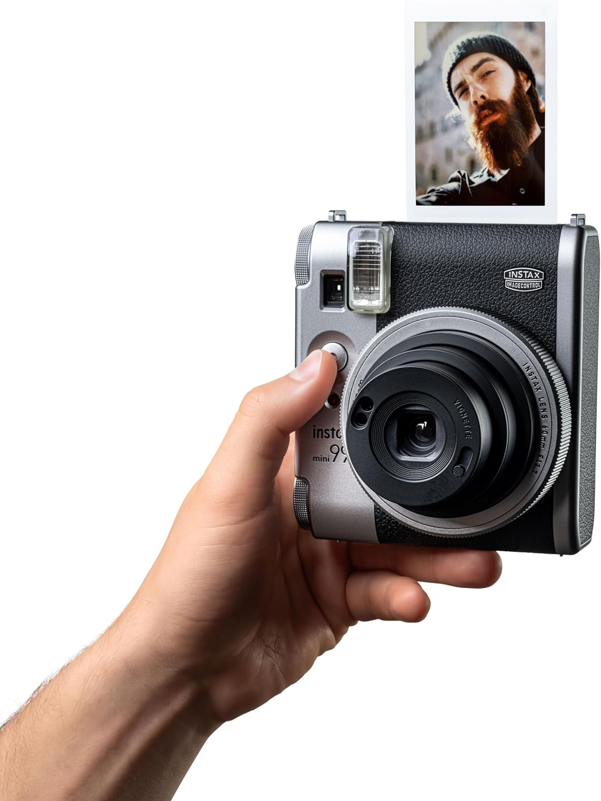Una mano sostiene una cámara Instax plateada y negra expulsando una foto.