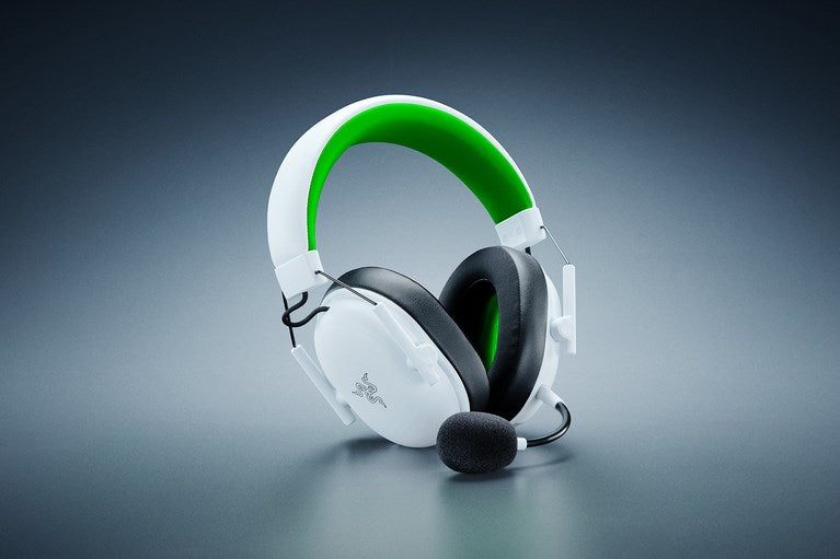 Auriculares para juegos en blanco y negro con diadema interior verde y micrófono adjunto.