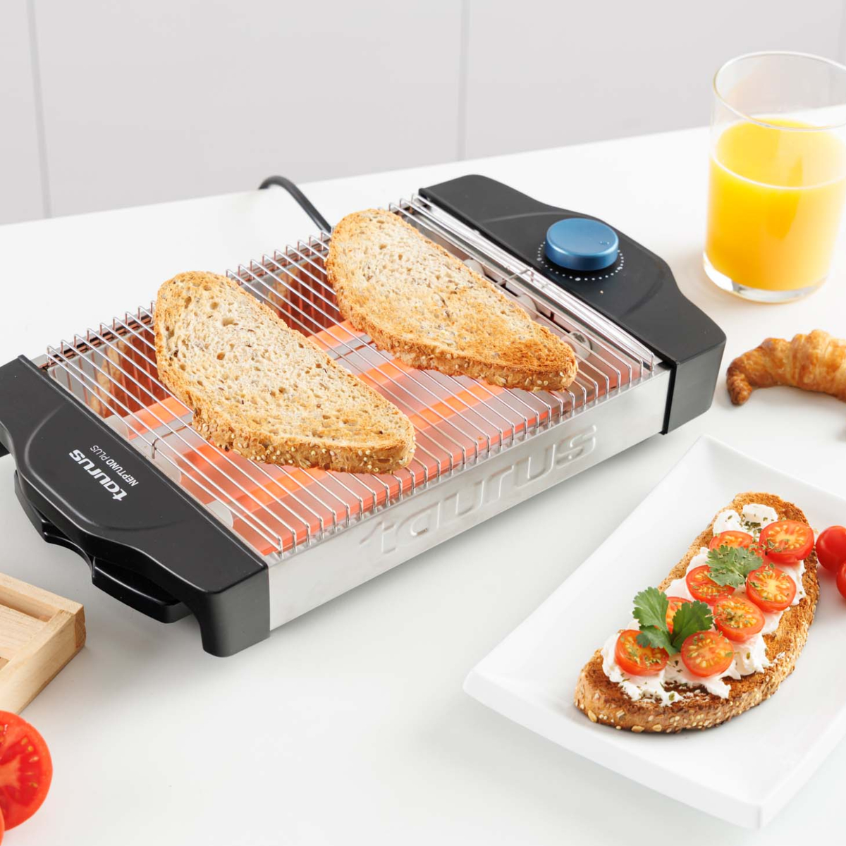 Dos rebanadas de pan se tuestan en una parrilla eléctrica, con jugo y tostadas con queso y tomates.