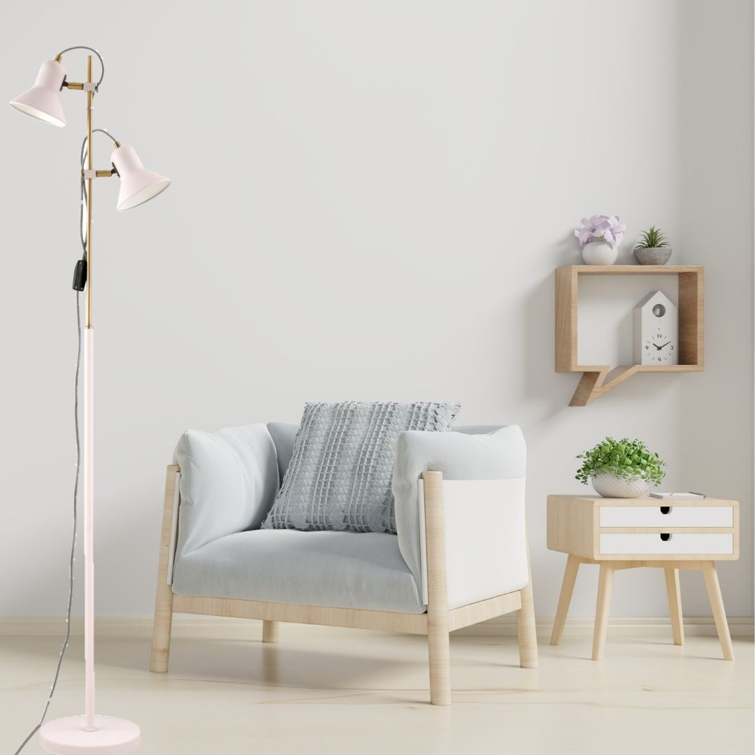 Una habitación luminosa con un sillón claro, una lámpara rosa, una mesita de madera y un estante en la pared blanca.