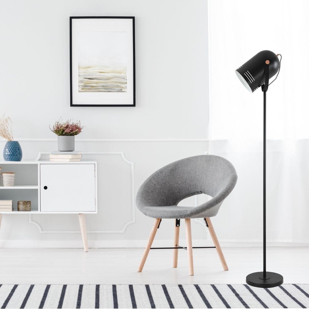 Una silla gris, una lámpara de pie negra y un armario blanco en una habitación luminosa.