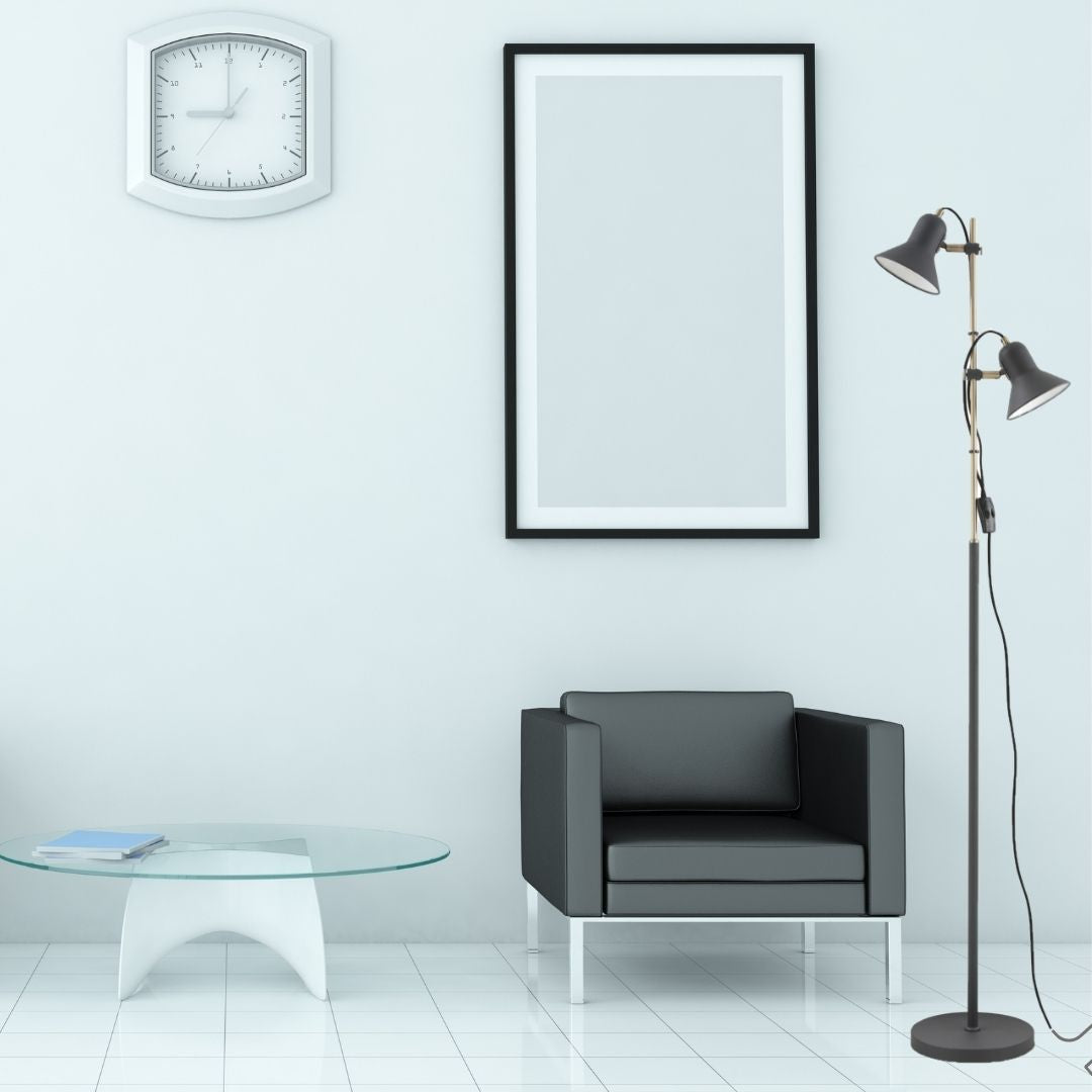 Una habitación minimalista con sillón negro, lámpara, reloj, mesa y cuadro en la pared blanca.