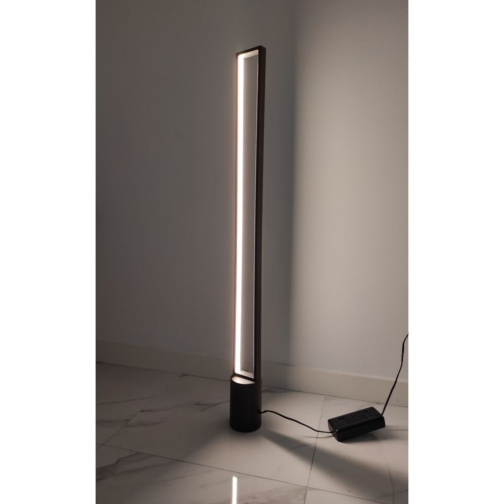Una lámpara de pie rectangular y delgada con luz vertical se encuentra sobre suelo de mármol blanco.