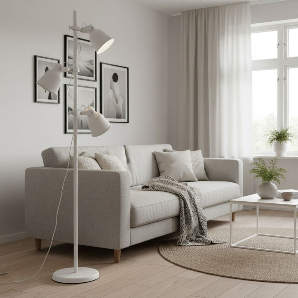 Una lámpara de pie blanca junto a un sofá gris en un salón luminoso con cuadros enmarcados.