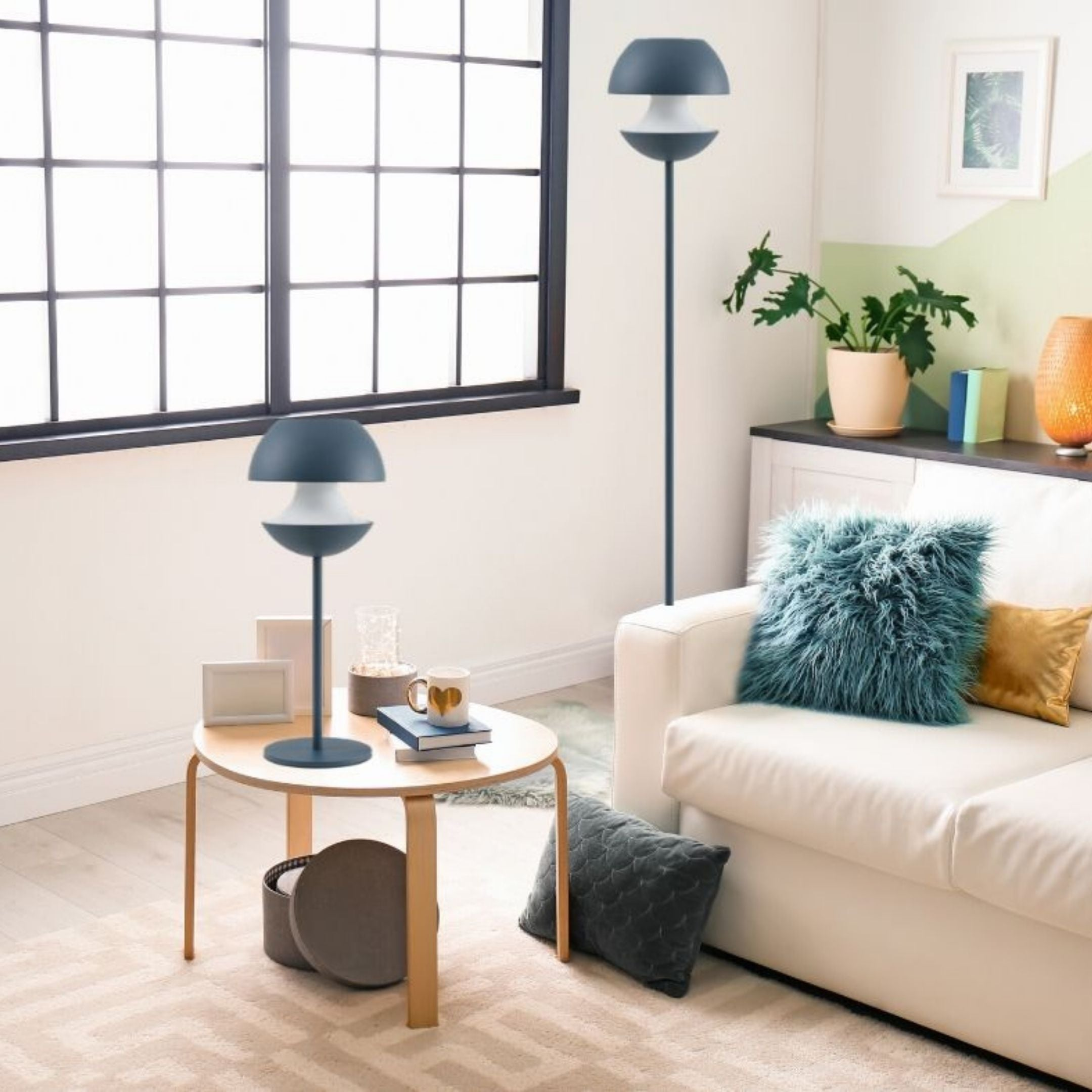 Lámparas modernas de pie y de mesa grises en una sala de estar luminosa con sofá blanco.