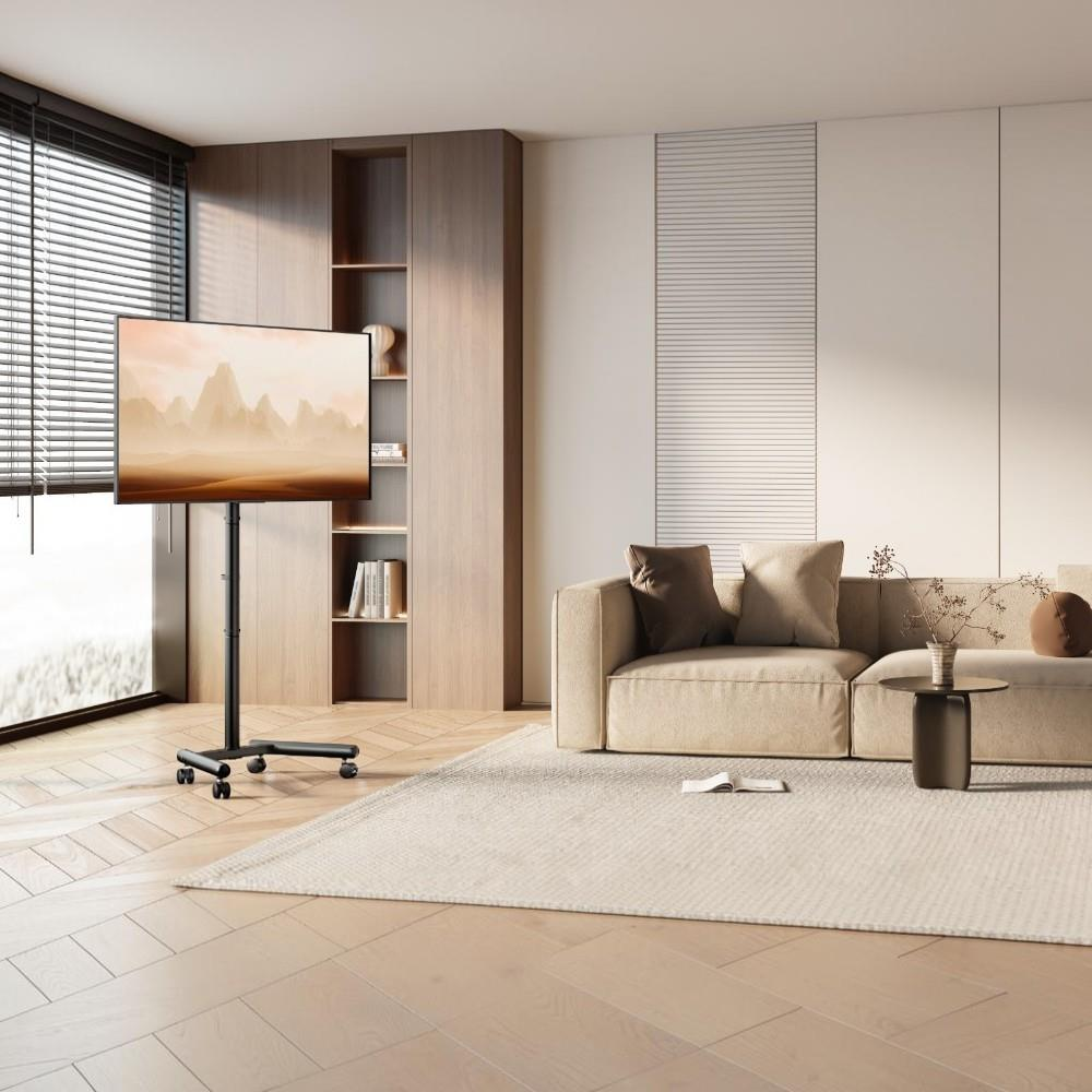 Bej koltuklu aydınlık modern oturma odasında tekerlekli ayak üzerinde bir TV.