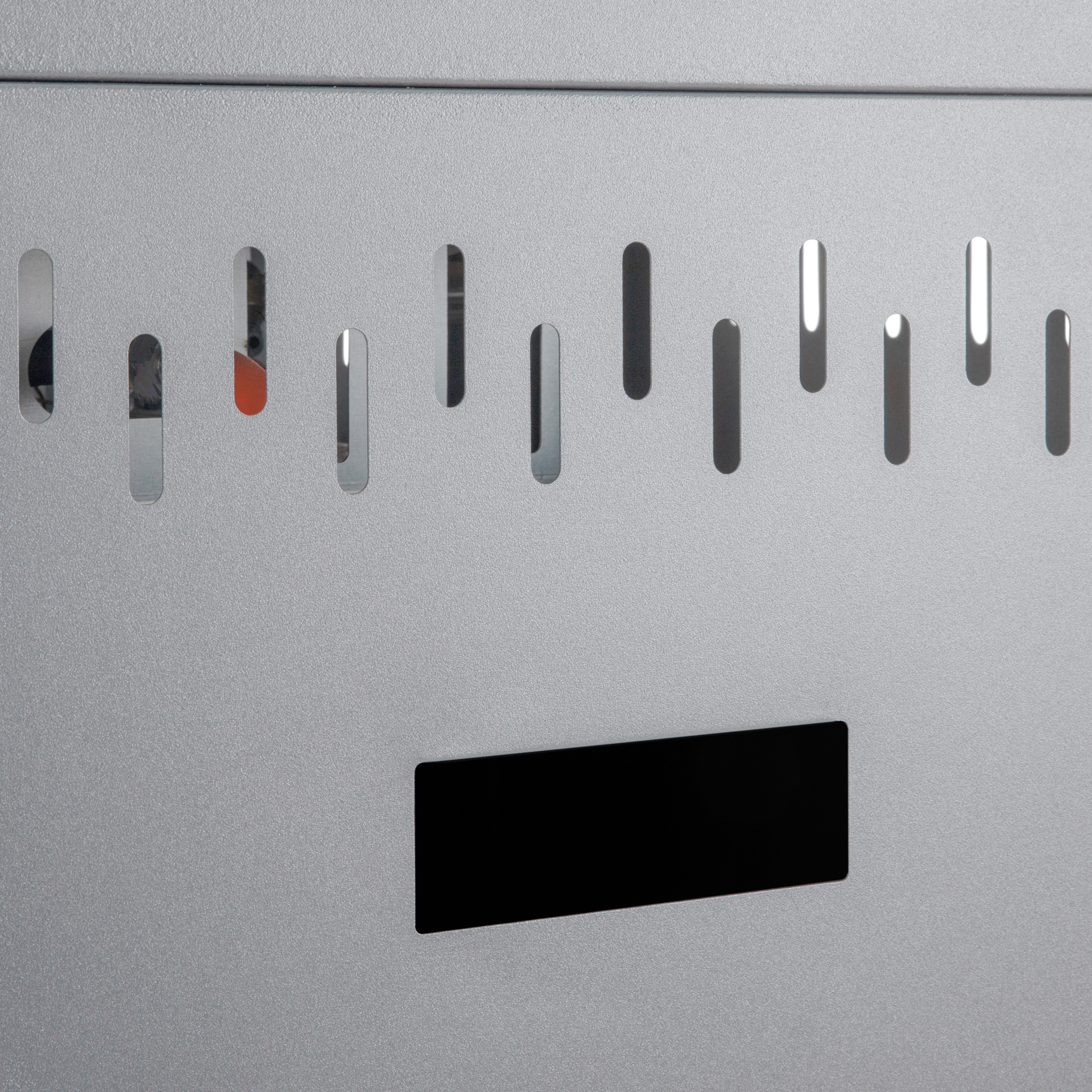 Graue Metalloberfläche mit einer Reihe vertikaler Lüftungsschlitze und einem schwarzen rechteckigen Display unten.