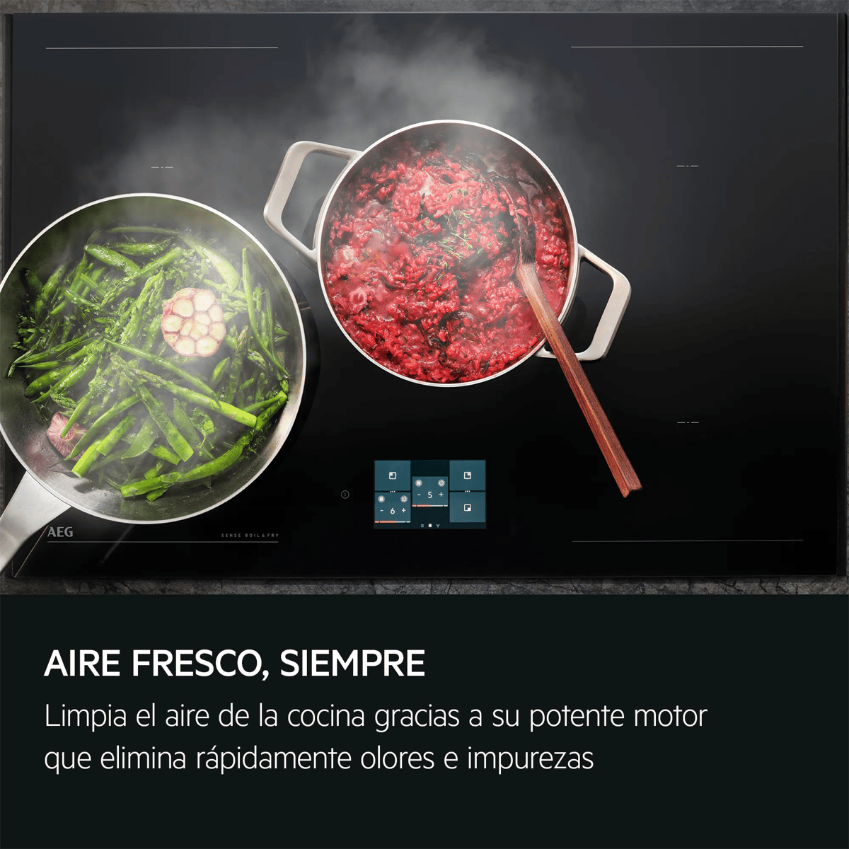 Dos ollas con espárragos verdes y comida roja en una placa de inducción negra con vapor.