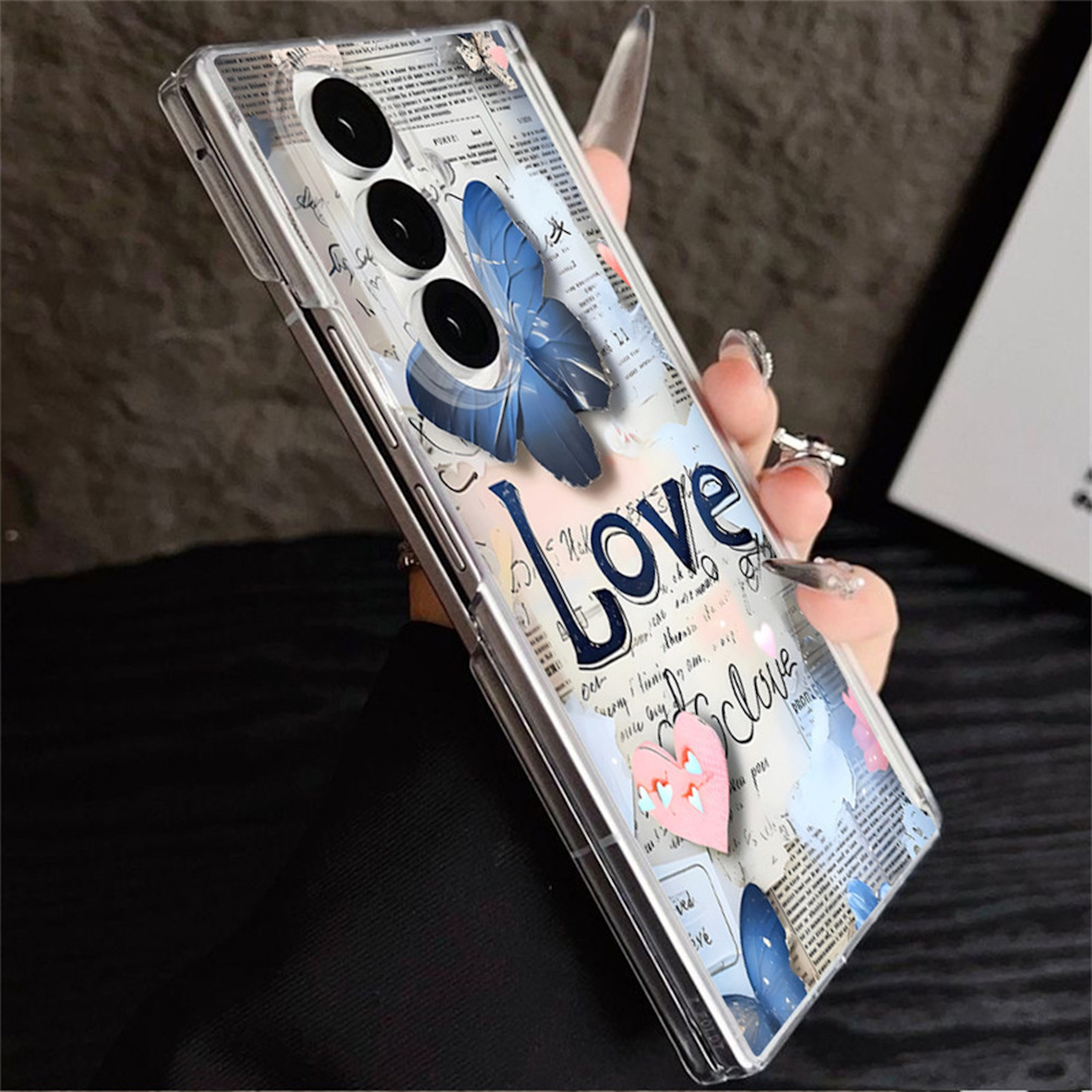 Transparente Handyhülle mit blauen Schmetterlingen, Zeitungsausschnitten und dem Wort Love auf weißem Hintergrund.