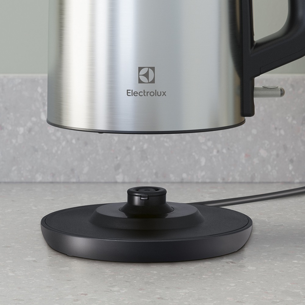 Un bollitore elettrico Electrolux in acciaio inossidabile fluttua sopra la sua base nera.