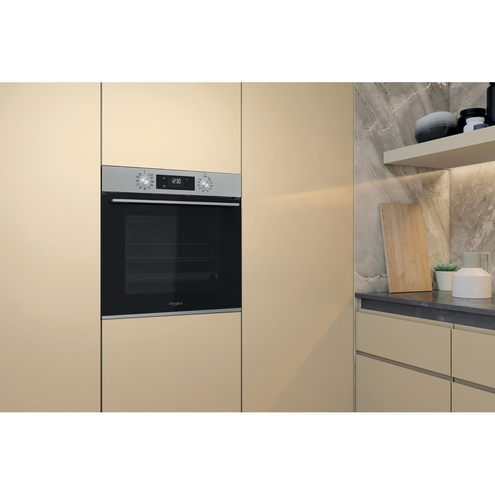 Ein moderner, in die beigen Küchenmöbel integrierter Backofen mit schwarzem Glas und Edelstahlblende.