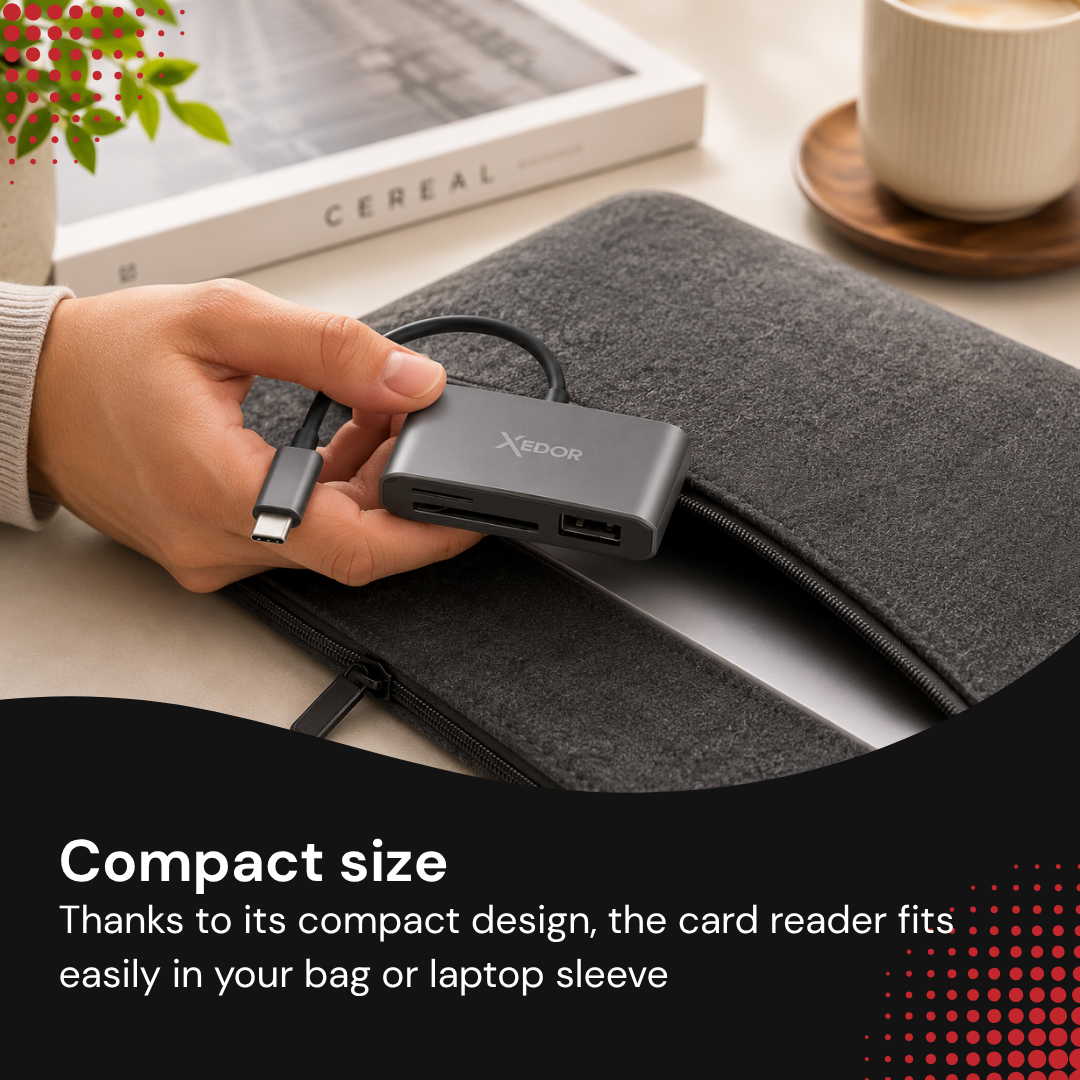 A hand holds a gray USB-C hub next to a laptop sleeve, a book, and a coffee cup.