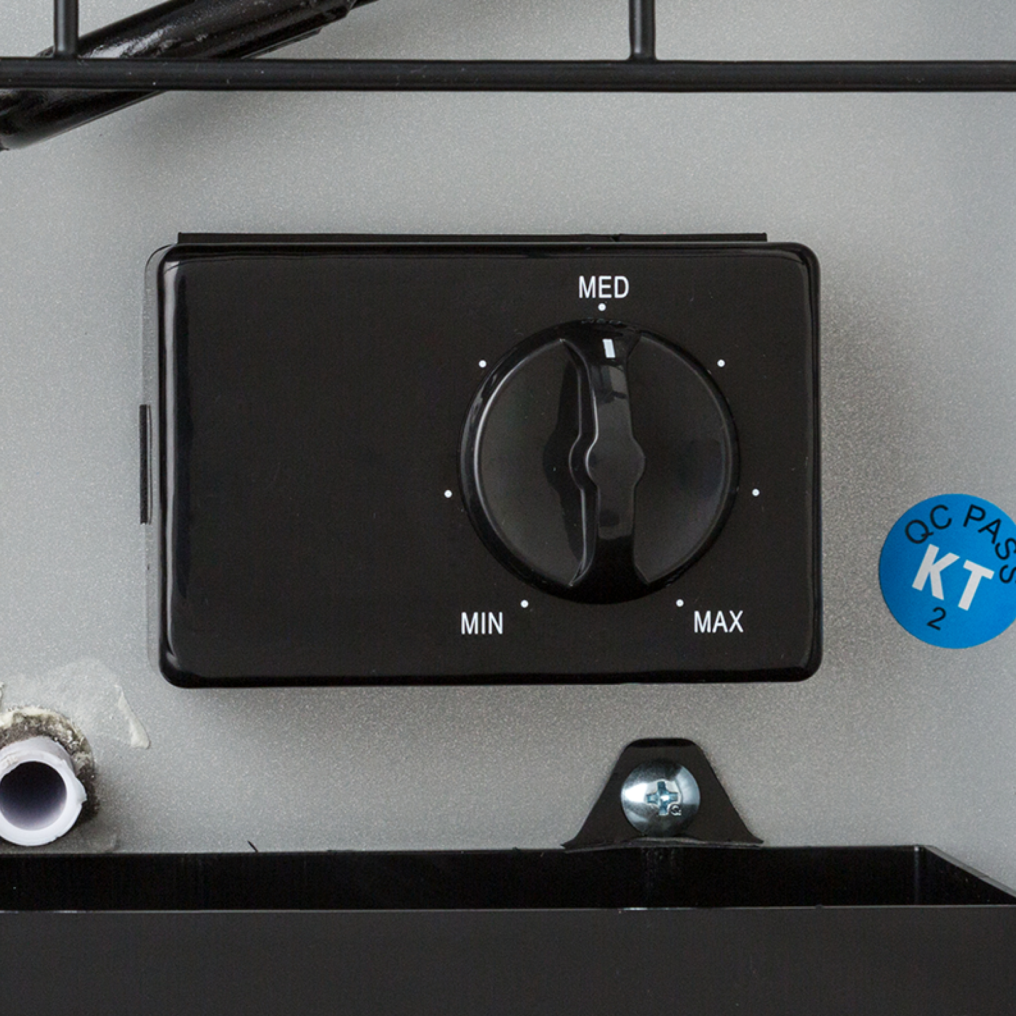 Una perilla de control redonda negra con niveles Min, Med y Max en una superficie de metal gris.