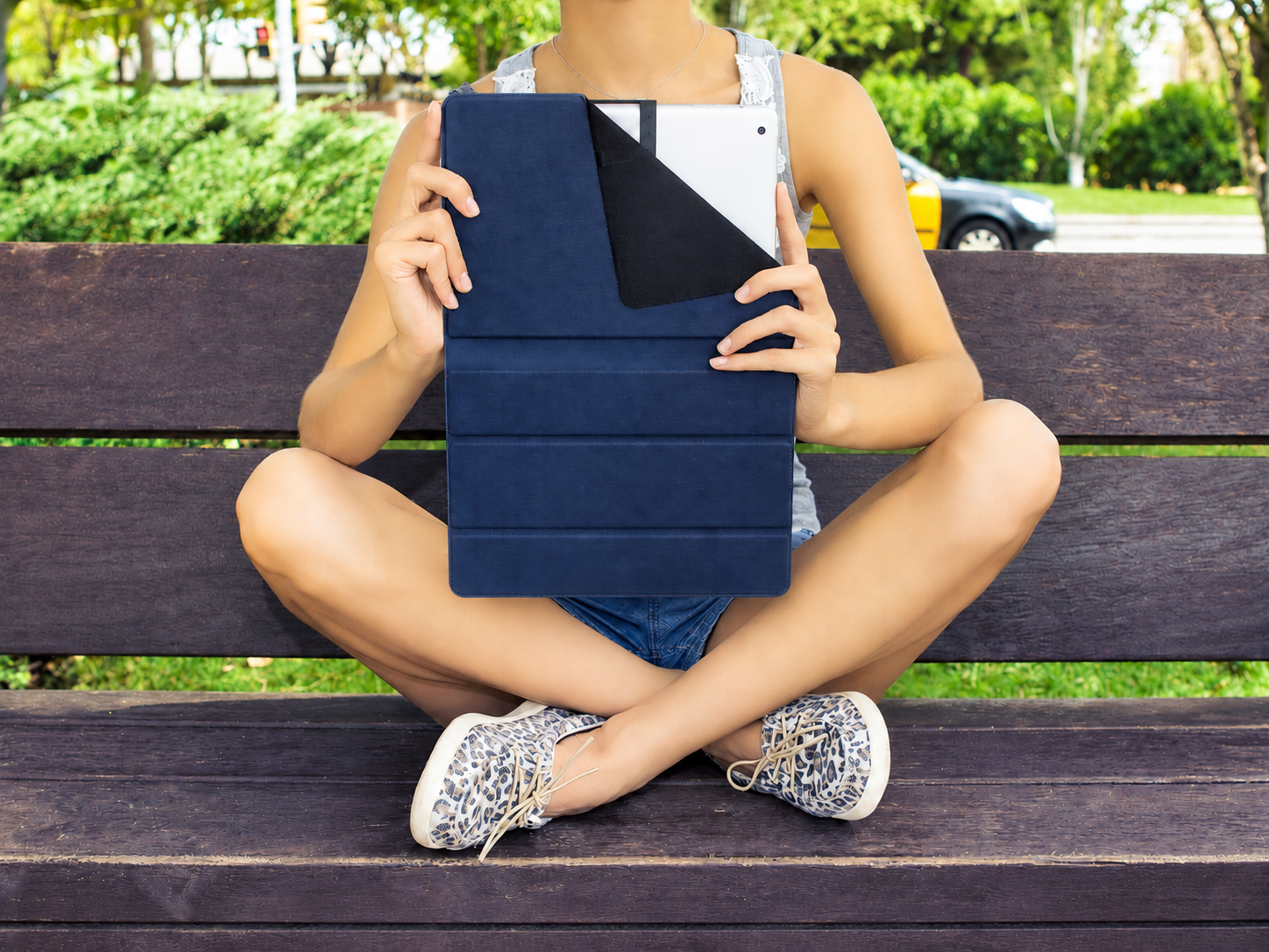 Una mujer está sentada en un banco sosteniendo una funda azul para tablet.
