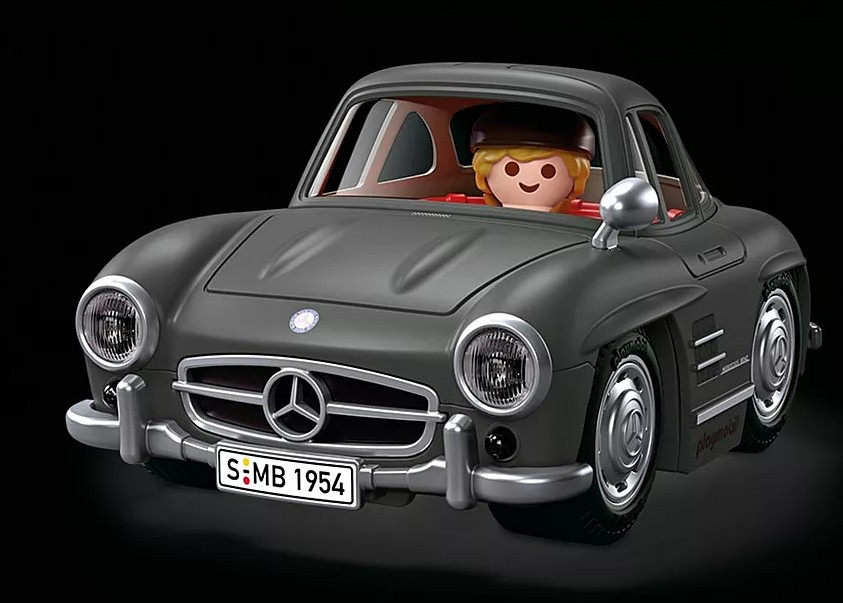 Siyah arka planda direksiyonda bir figür olan gri bir retro Playmobil oyuncak araba.