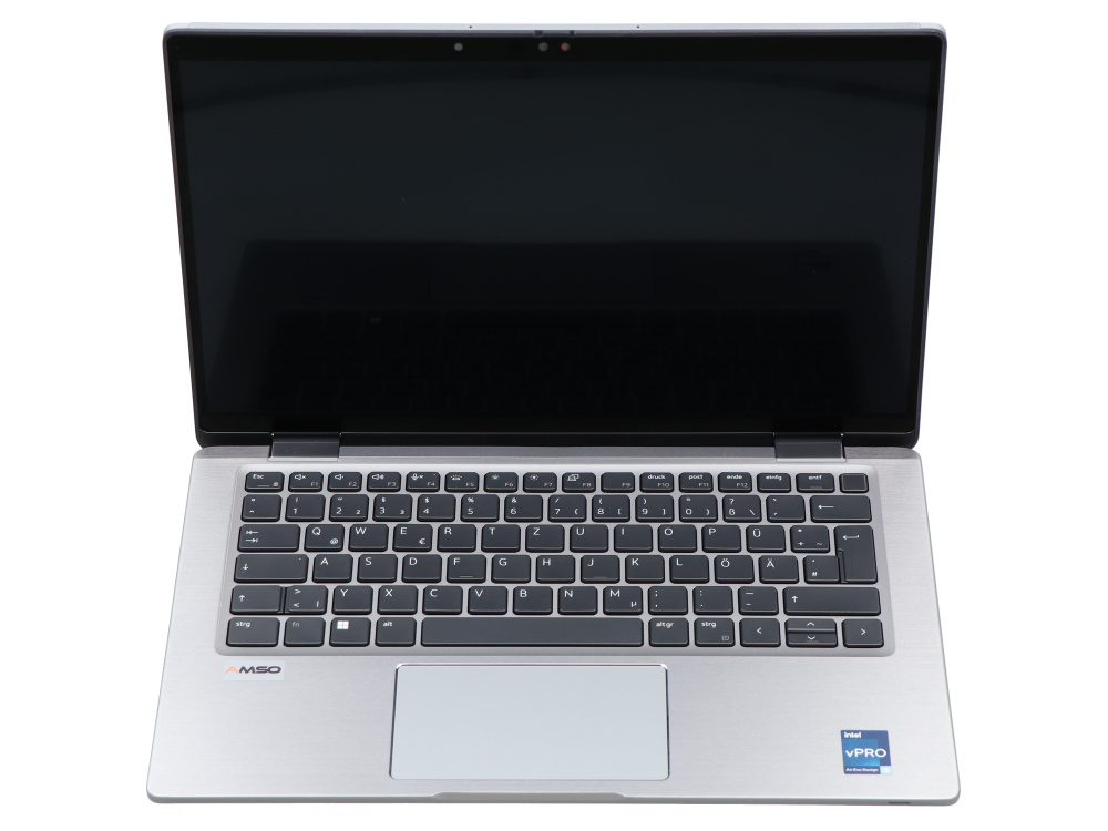 Srebrny laptop z niemiecką klawiaturą i czarnym ekranem, widoczny z góry.