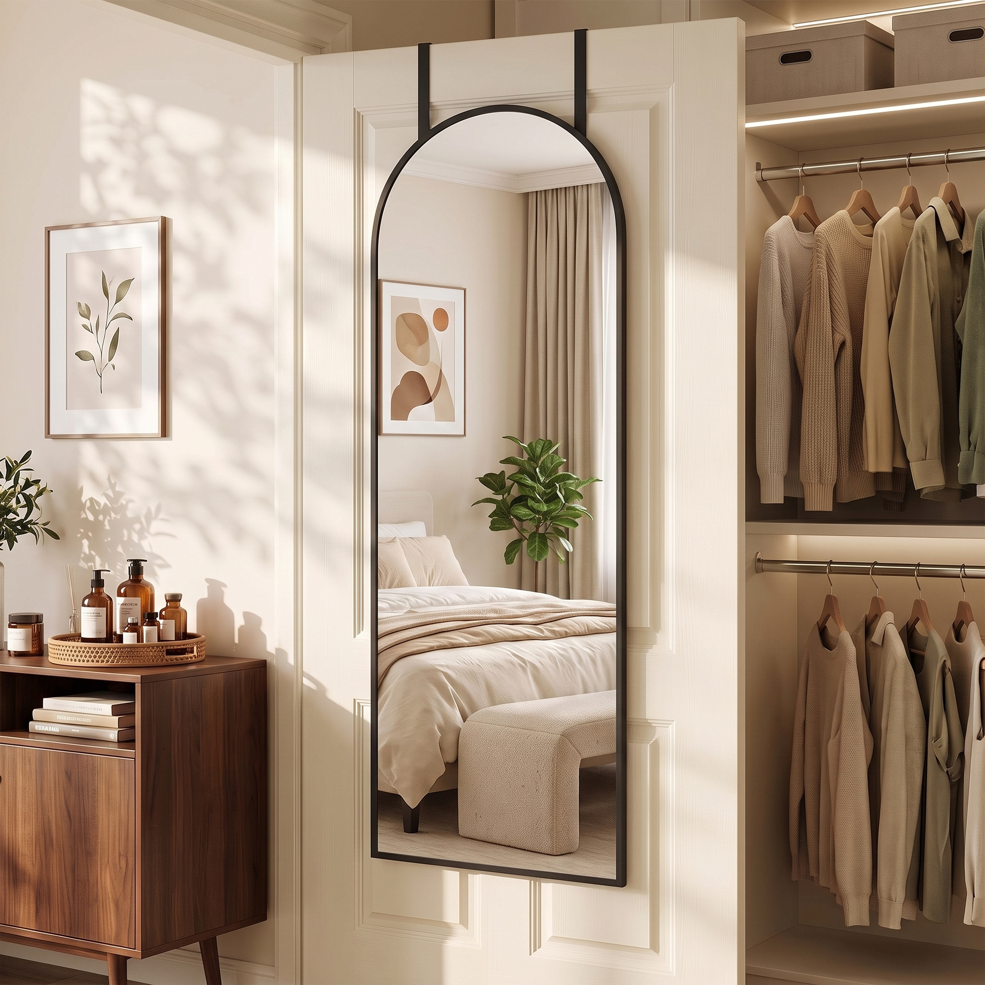 Un espejo arqueado cuelga de una puerta blanca, junto a un mueble con botellas y un armario de ropa.