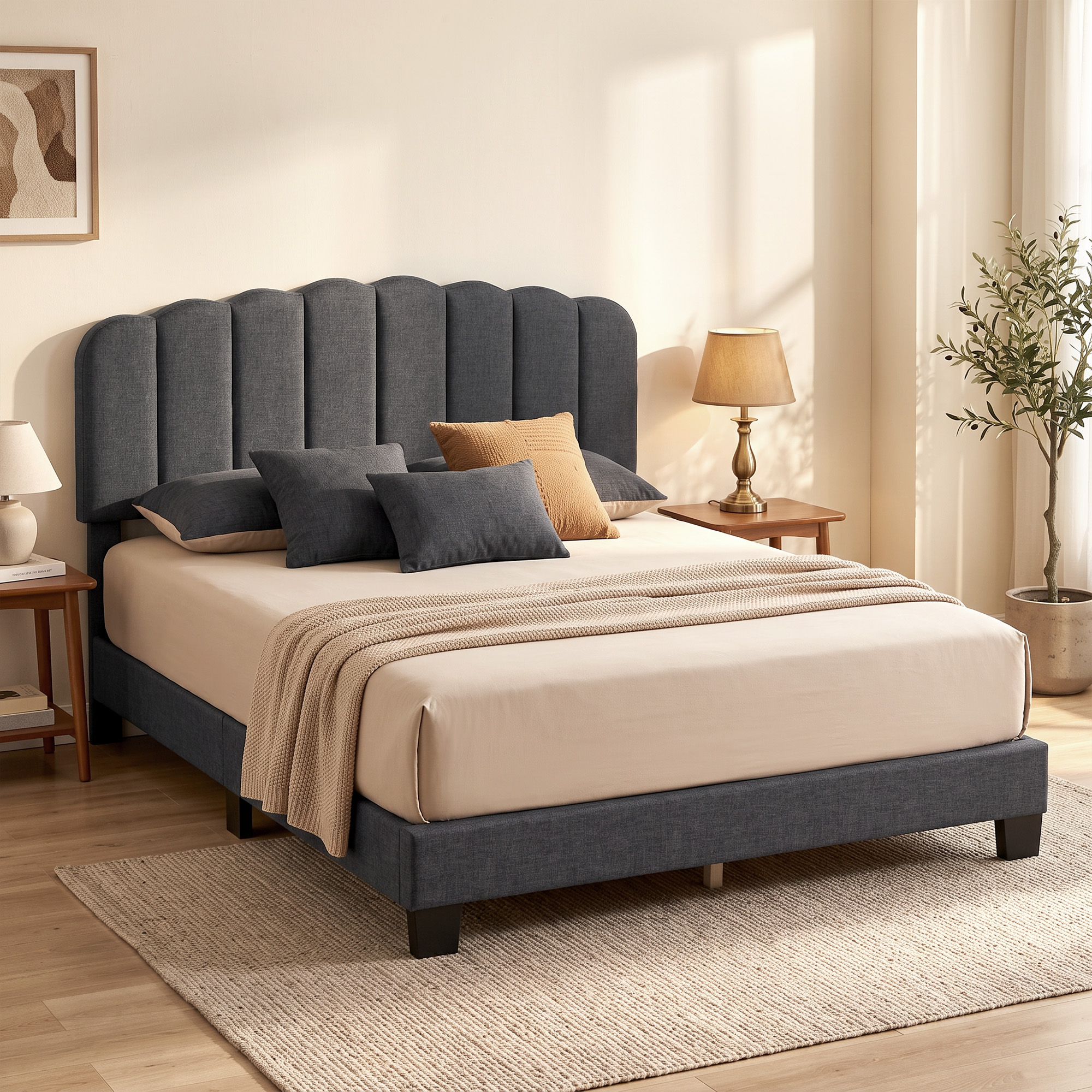 Una cama tapizada en gris con ropa de cama beis, cojines y mesillas de noche en una habitación luminosa.