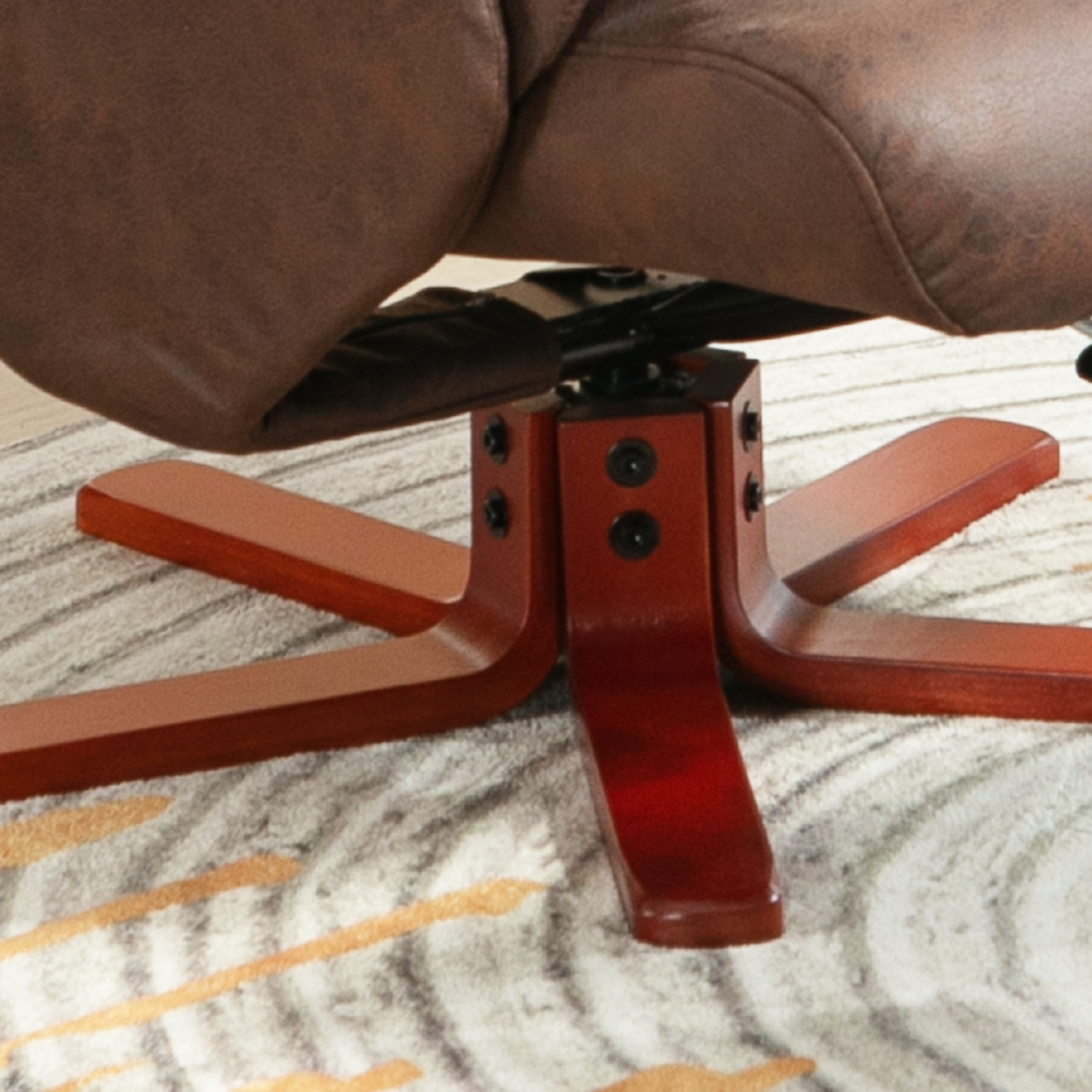 Sillón de cuero marrón con base de estrella de madera rojiza sobre una alfombra.