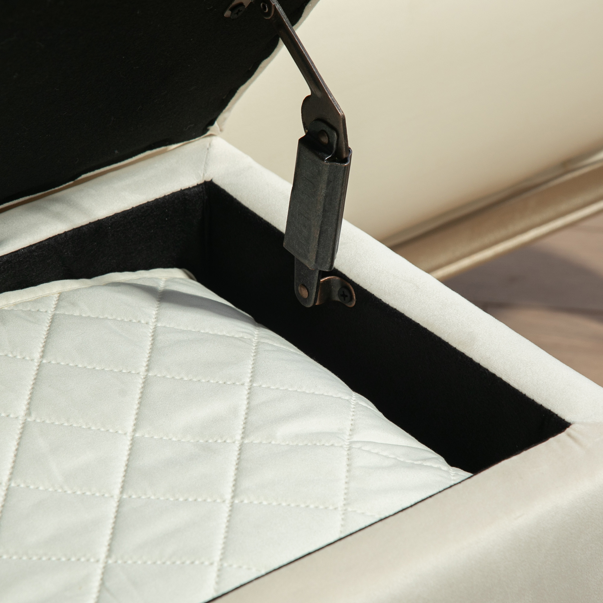 Puf de almacenamiento beige abierto con interior negro y bisagra.