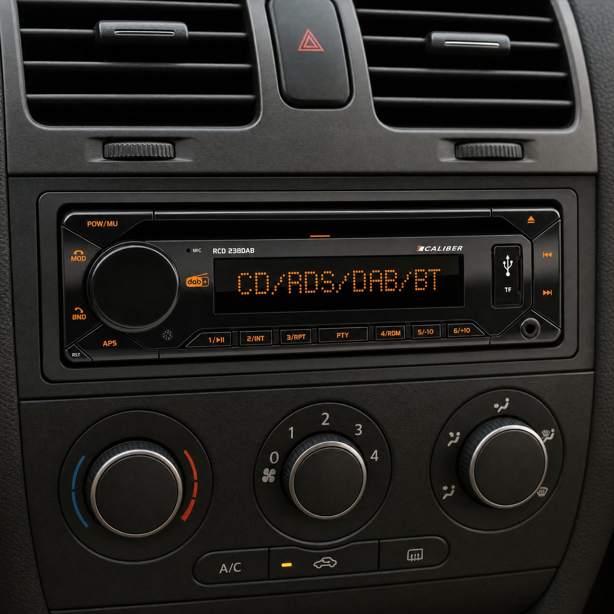 A car audio system with a digital display in a car dashboard, surrounded by air vents and climate control knobs.