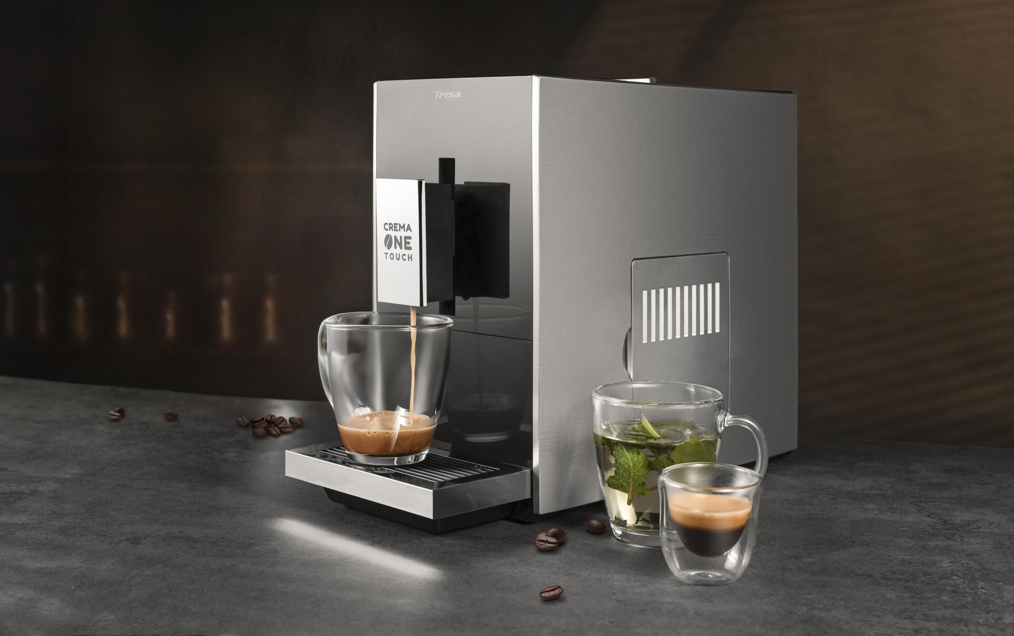Moderna macchina da caffè argentea che versa il caffè in una tazza, con tè e chicchi di caffè su un tavolo scuro.
