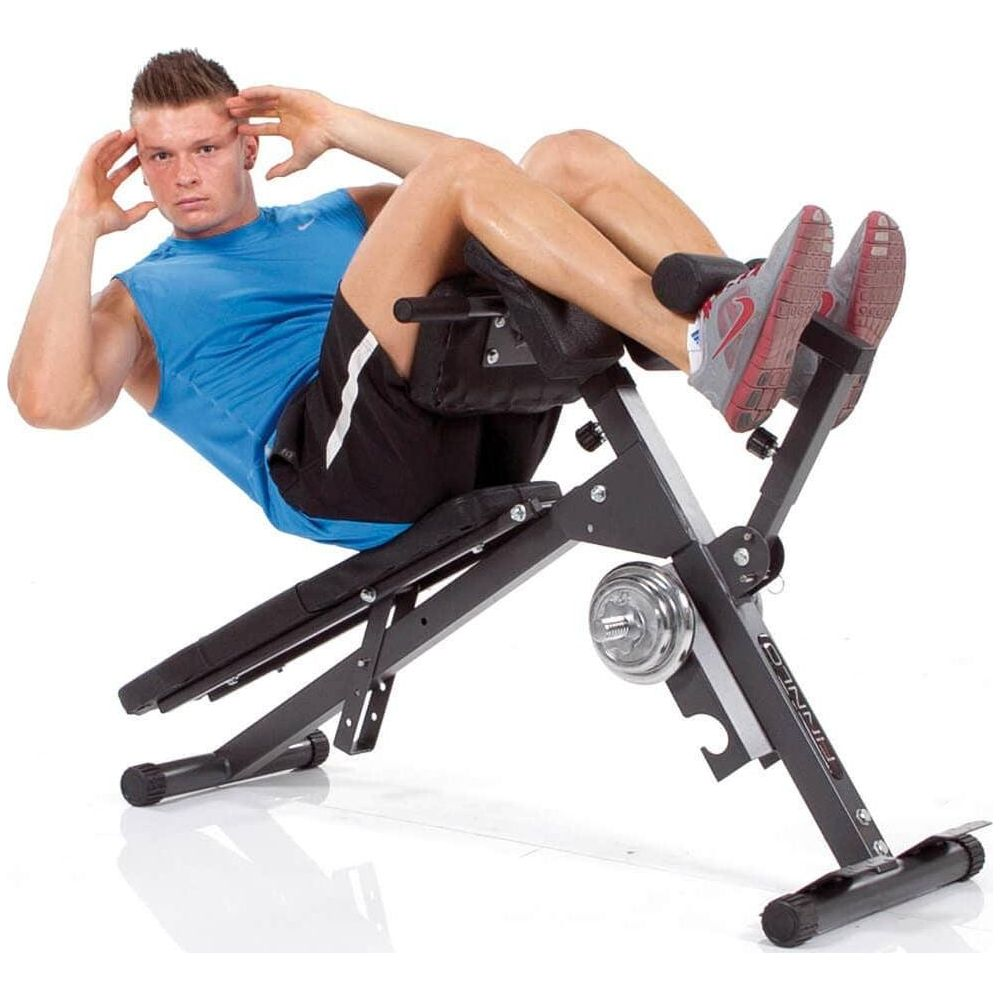 Ein Mann in blauem Shirt und schwarzen Shorts macht Sit-ups auf einer Schrägbank mit Gewichten.