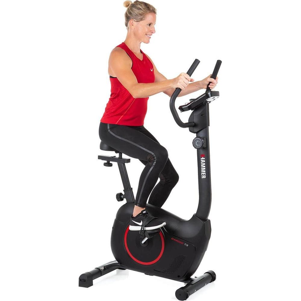 Frau in rotem Oberteil trainiert auf einem schwarzen Heimtrainer.