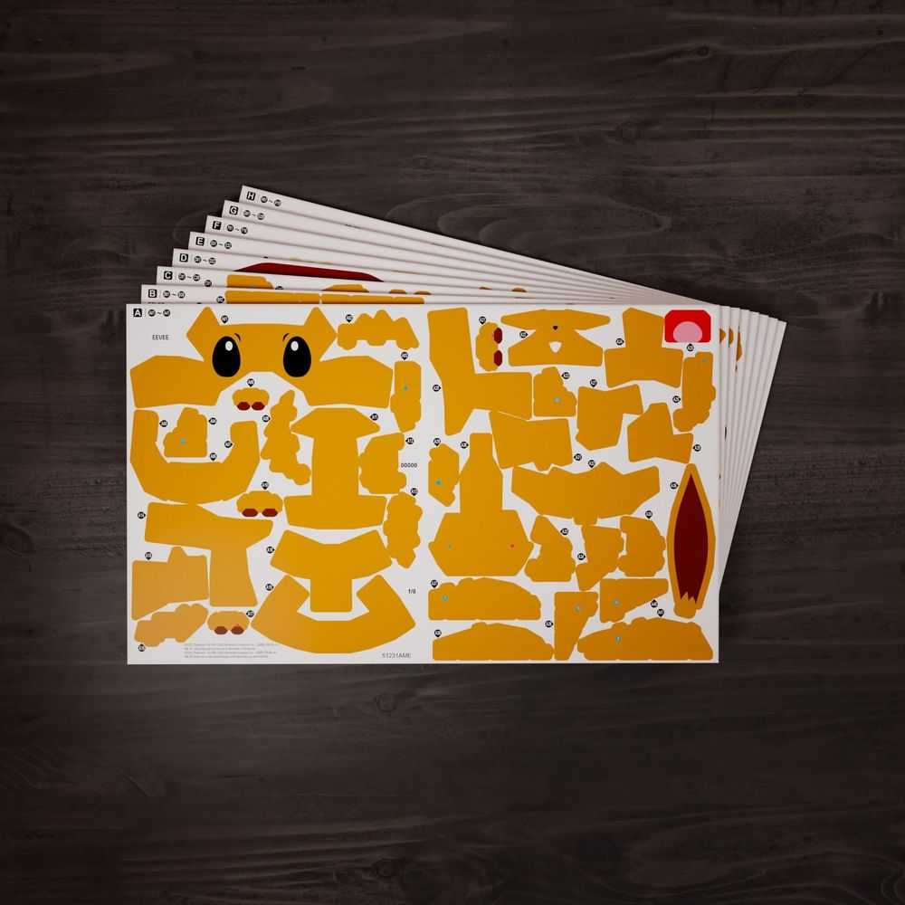 Pila de hojas de papel con piezas amarillas del modelo Eevee en una mesa de madera.