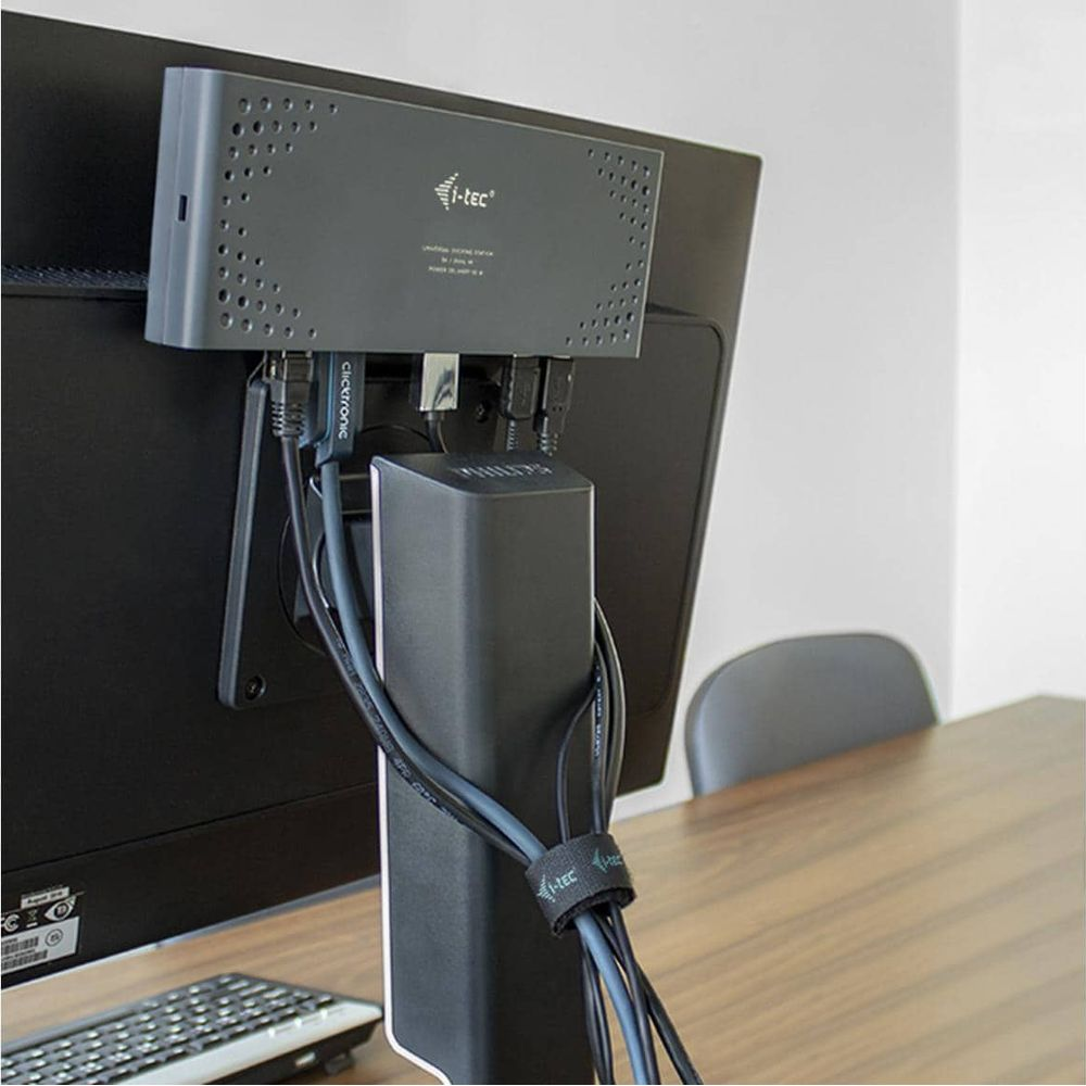 Eine graue Dockingstation ist an der Rückseite eines Monitors montiert, darunter sind mehrere Kabel gebündelt.