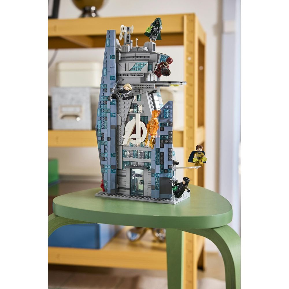 Una torre Lego Avengers detallada sobre un taburete verde, con varias minifiguras y un gran logotipo.