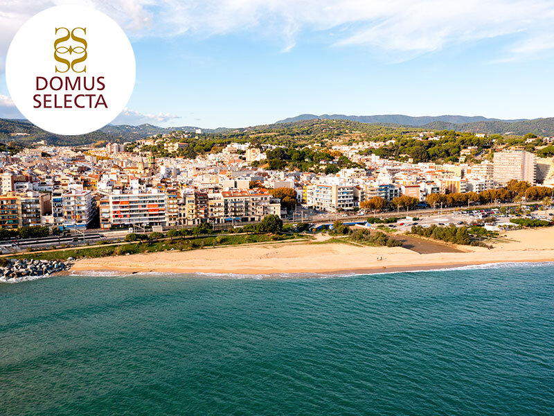 Vista aérea de una ciudad costera con playa, mar y colinas.
