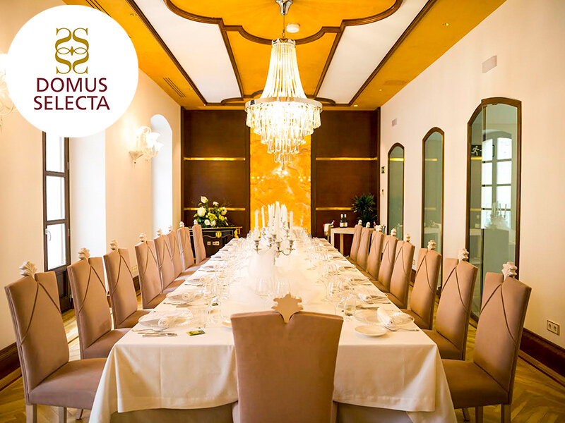 Mesa de comedor larga y elegante en un salón blanco con una lámpara.