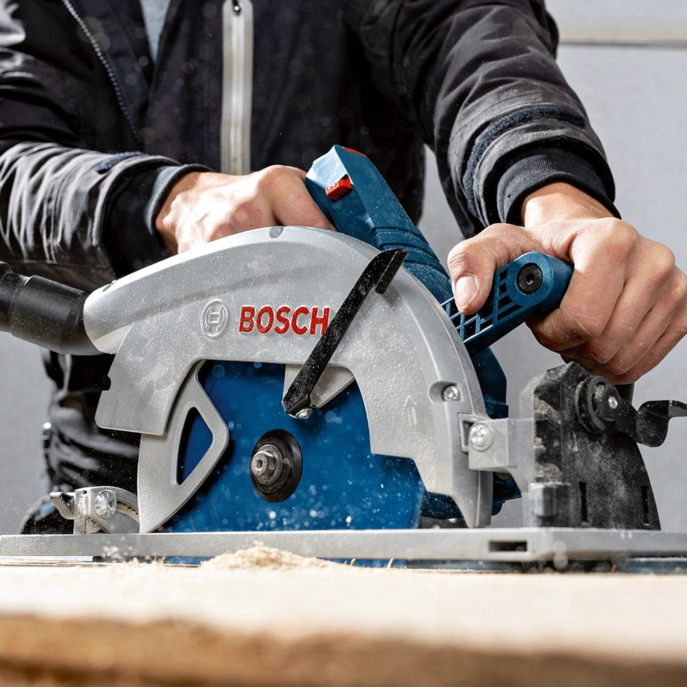 Person cutting wood with a blue and silver Bosch circular saw.