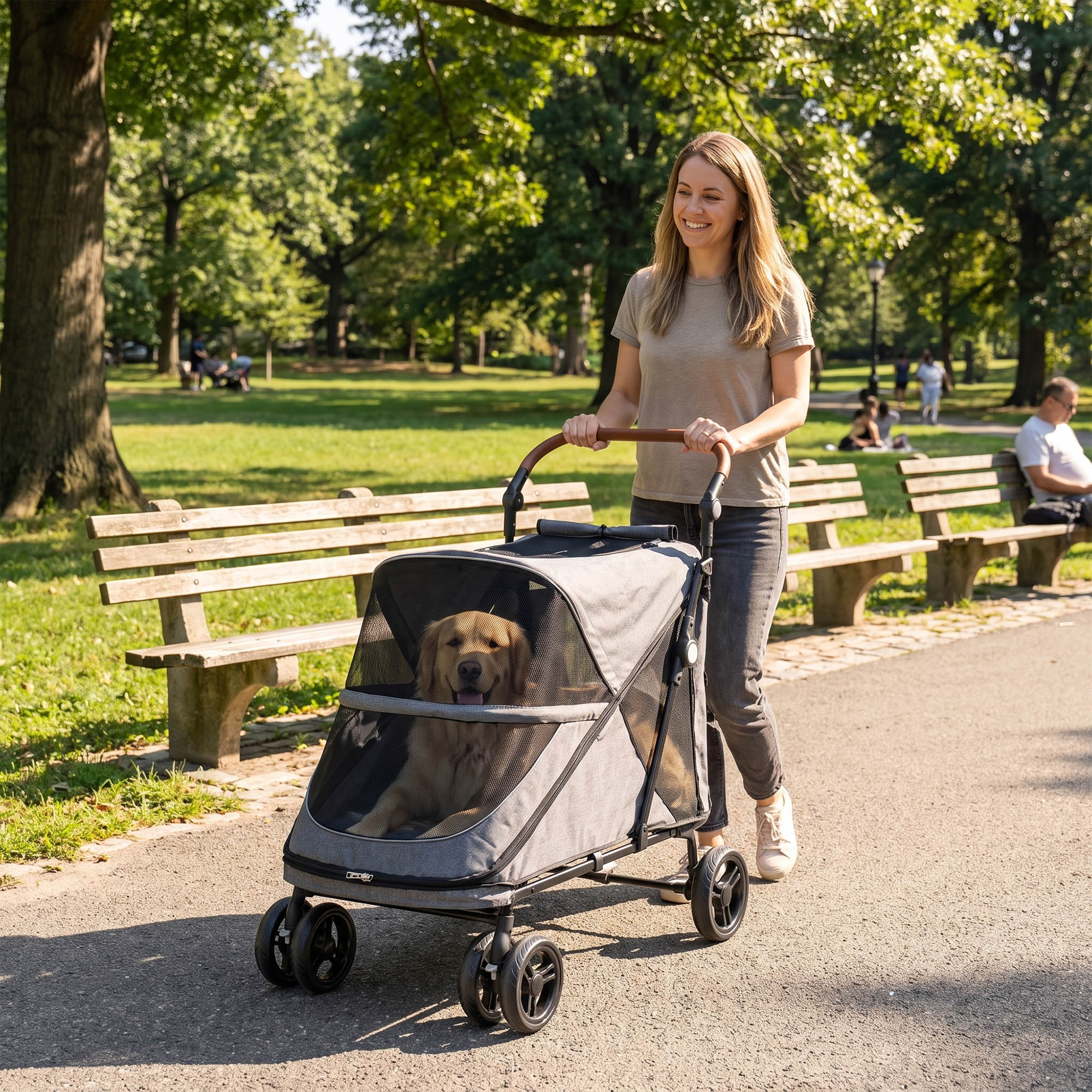 Una mujer empuja un carrito gris para mascotas con un golden retriever dentro en un parque soleado.