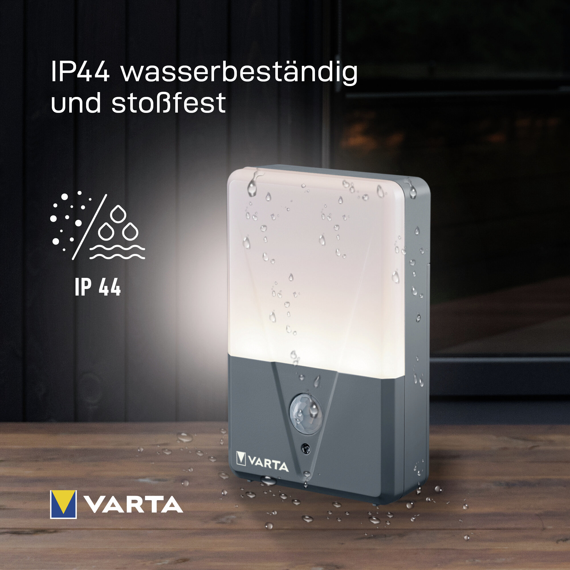 Wasserdichte Varta LED-Wandleuchte mit Bewegungsmelder auf einem Holztisch mit Wassertropfen.