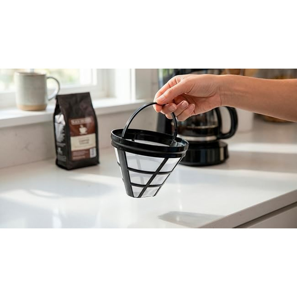 Una mano regge un filtro per caffè nero in cucina, con una macchina da caffè e un sacchetto di caffè sullo sfondo.